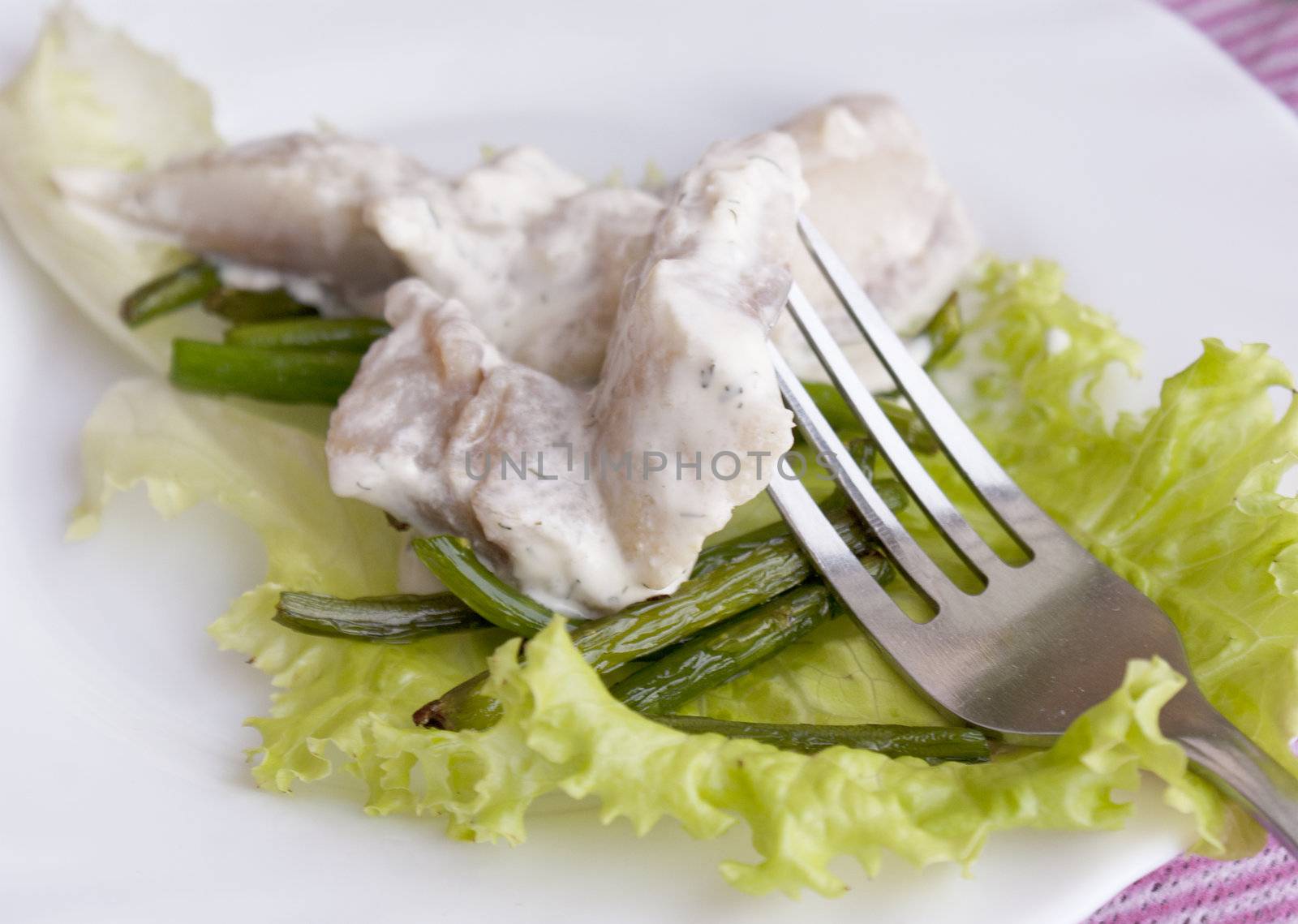 Appetizing marinaded herring with fried stalks of garlic