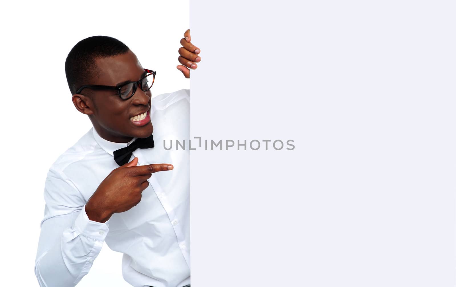 African young man pointing and looking at blank billboard wearing glasses