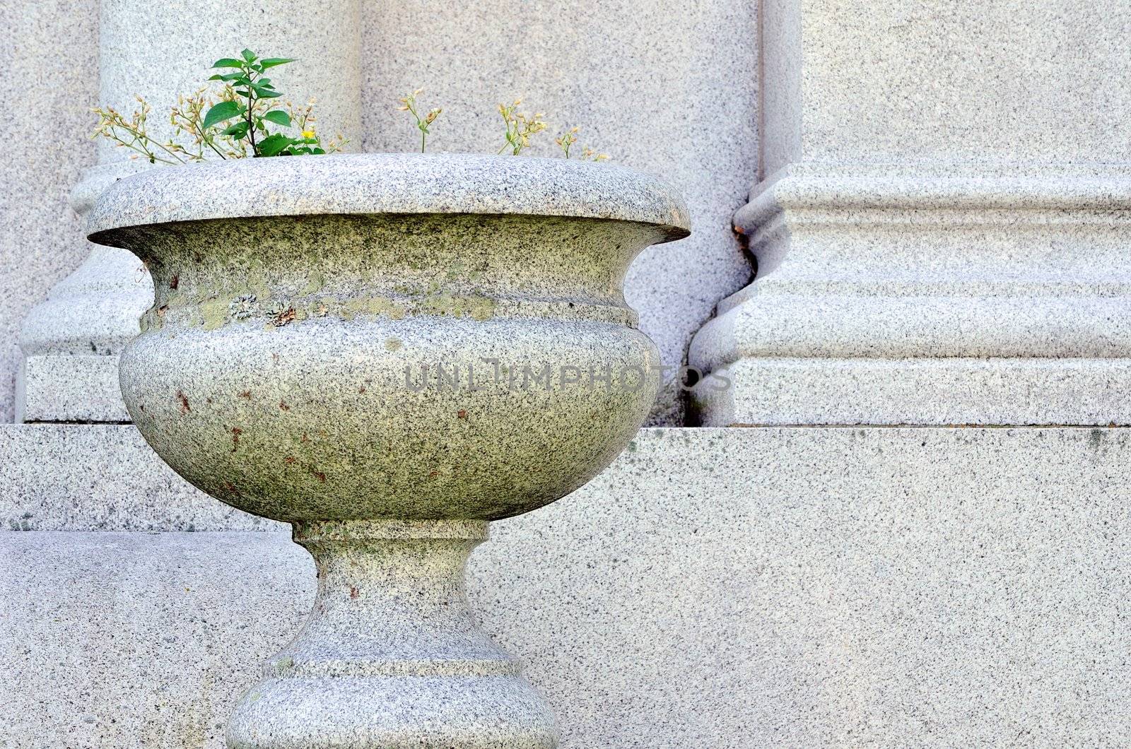 Stone Vase in a cemetery next to a headstone.