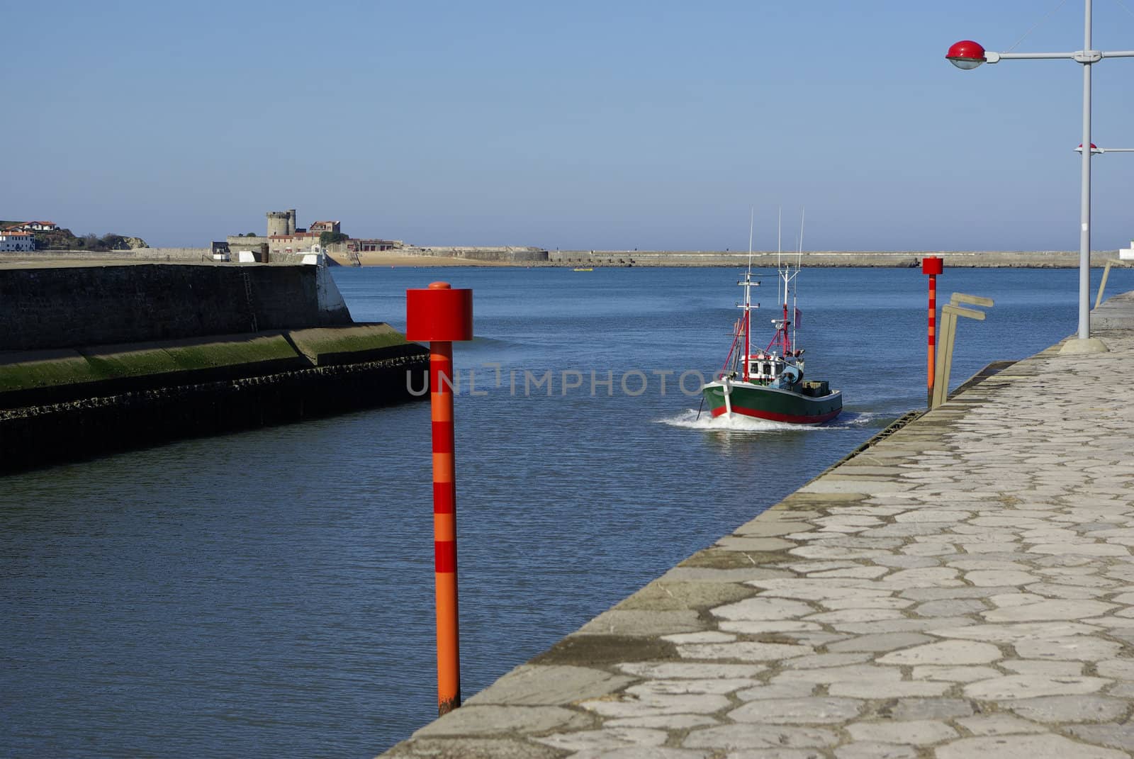 Little Boat in Entrance of an Harbor with blue sky and sea