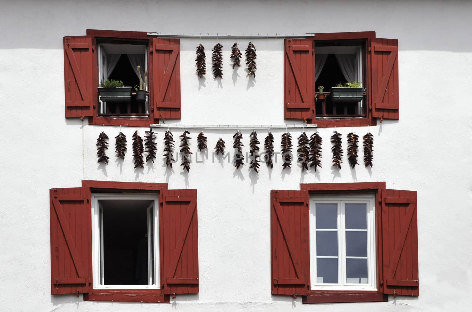 Red Spices hanging on a White Wall with Red Shutters by shkyo30