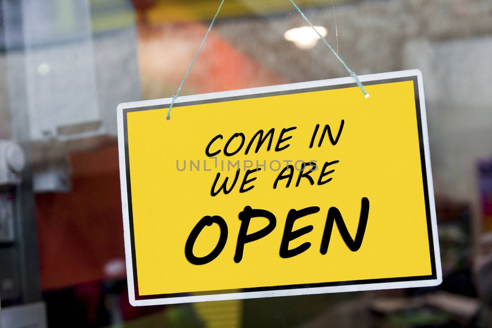 come in we are open sign hanging on a window door outside a restaurant, store, office or other