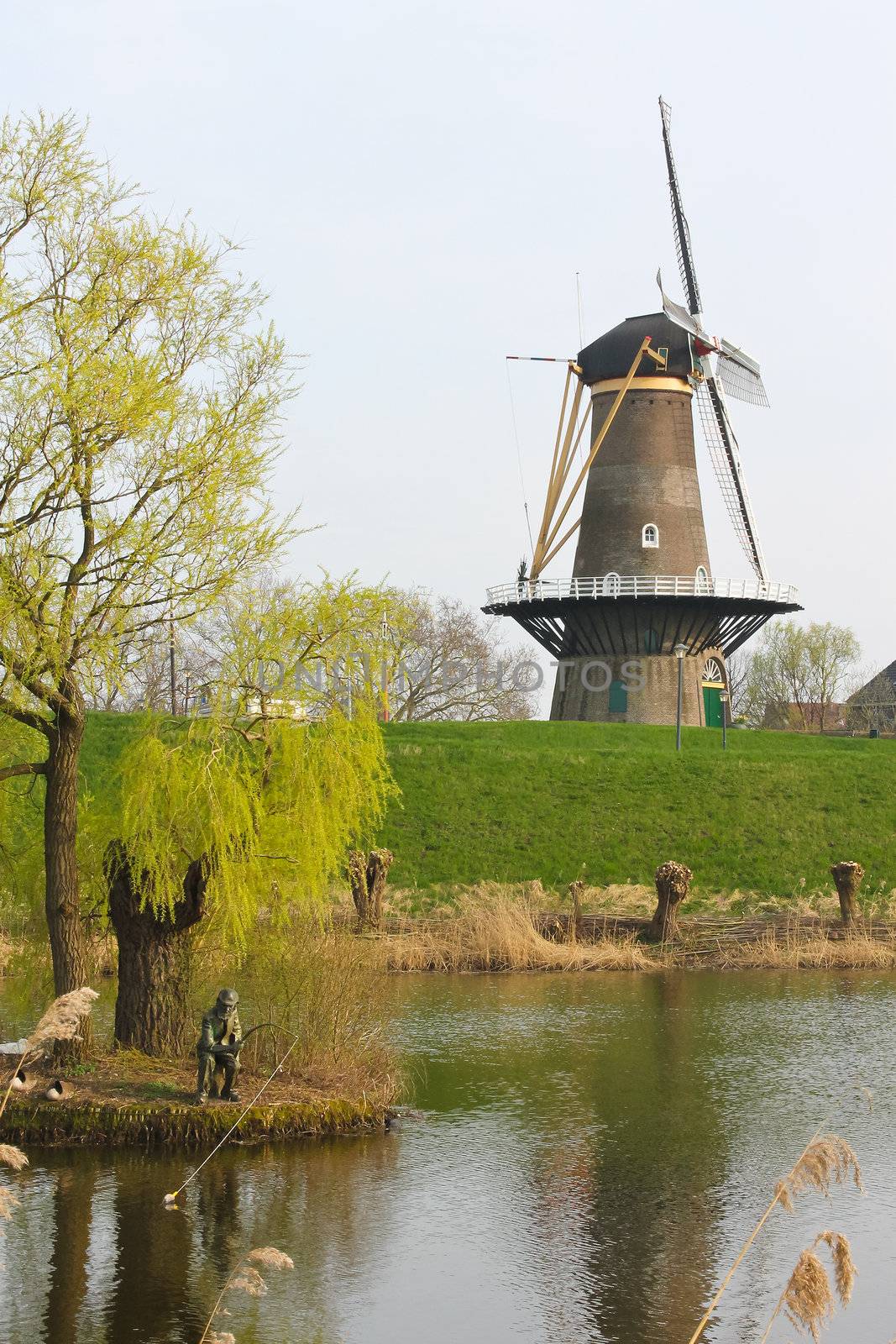 Statue of the fisherman on the background of a windmill in Gorinchem. Netherlands