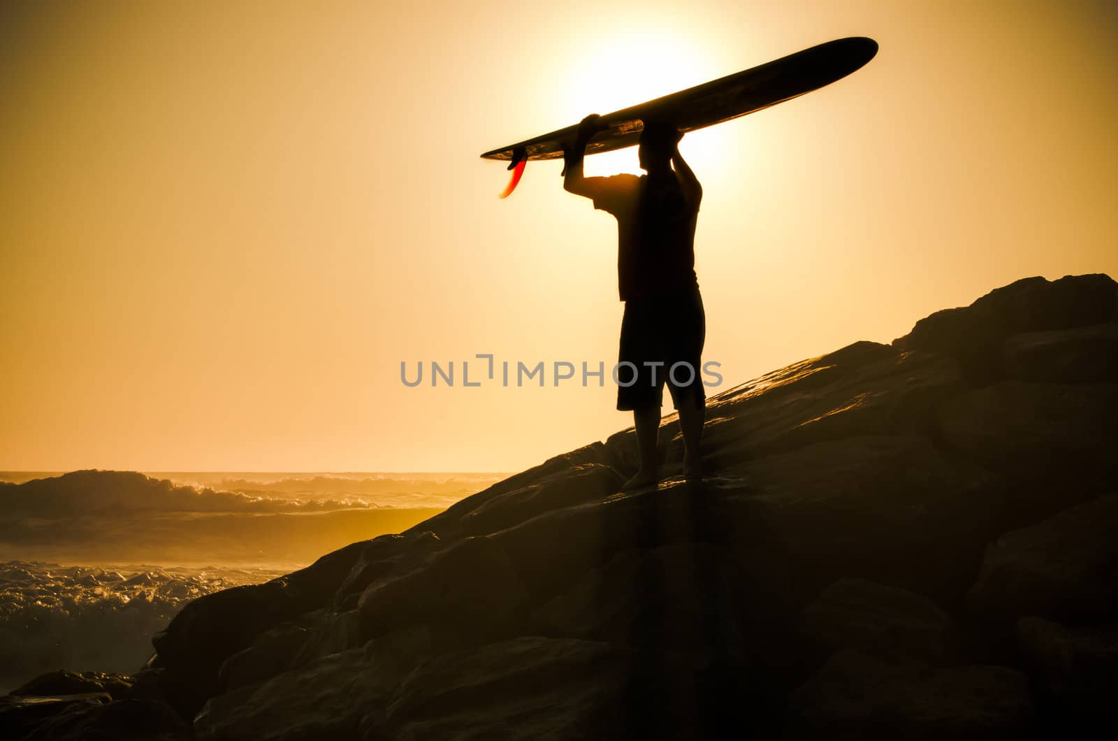 A long boarder watching the waves at sunset in Portugal.