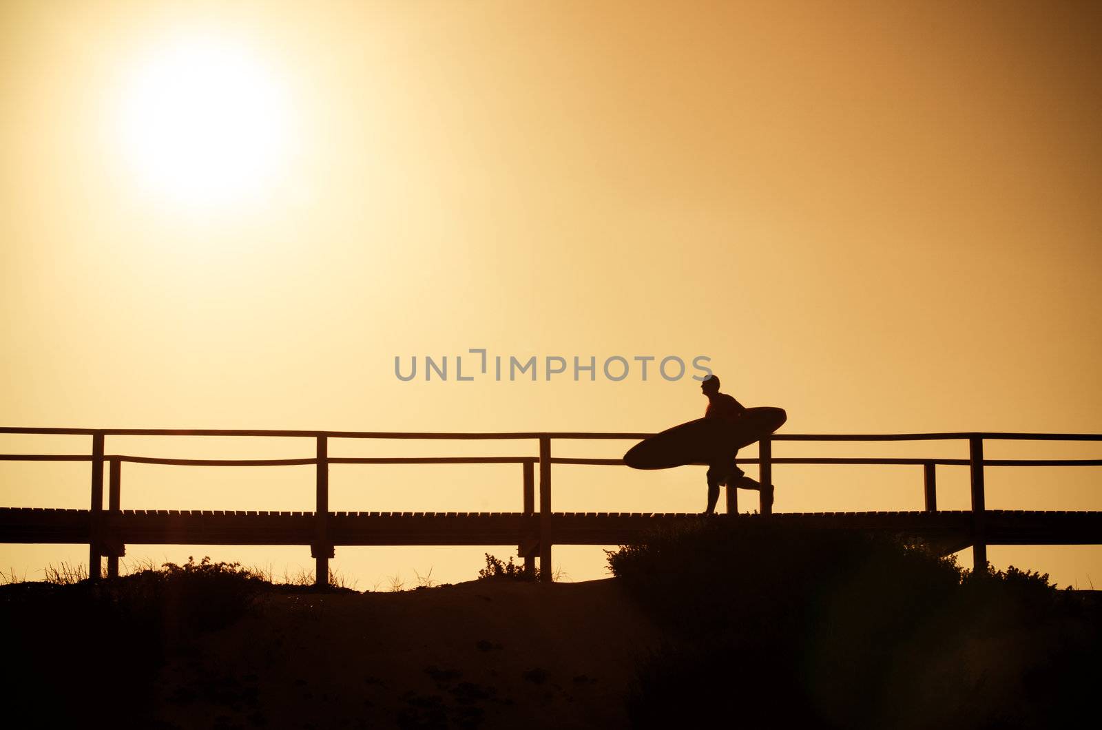 A surfer running to the beach at sunset in Portugal.