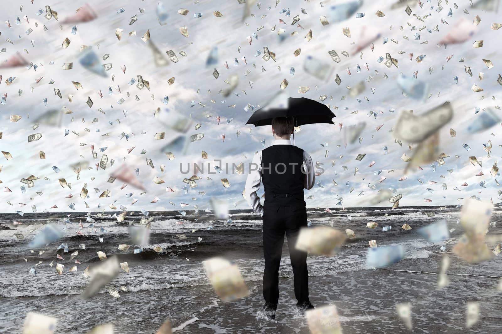 Young businessman standing with umbrella under money rain