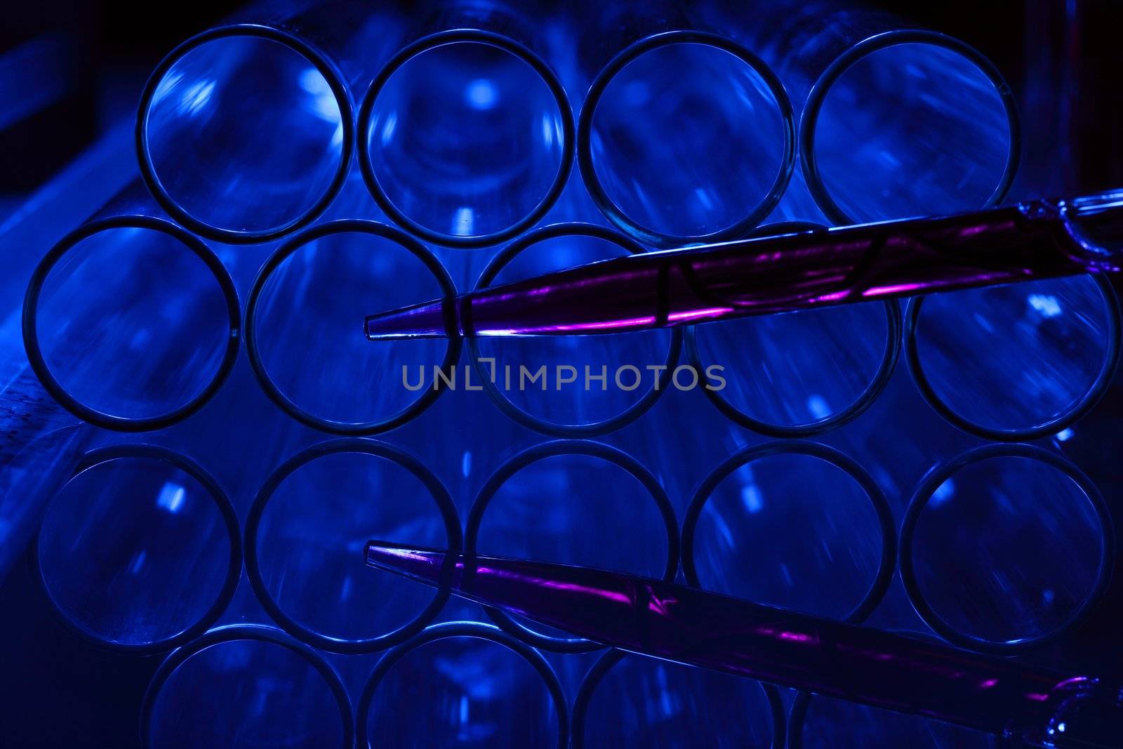 Glass chemistry tubes on a colour background