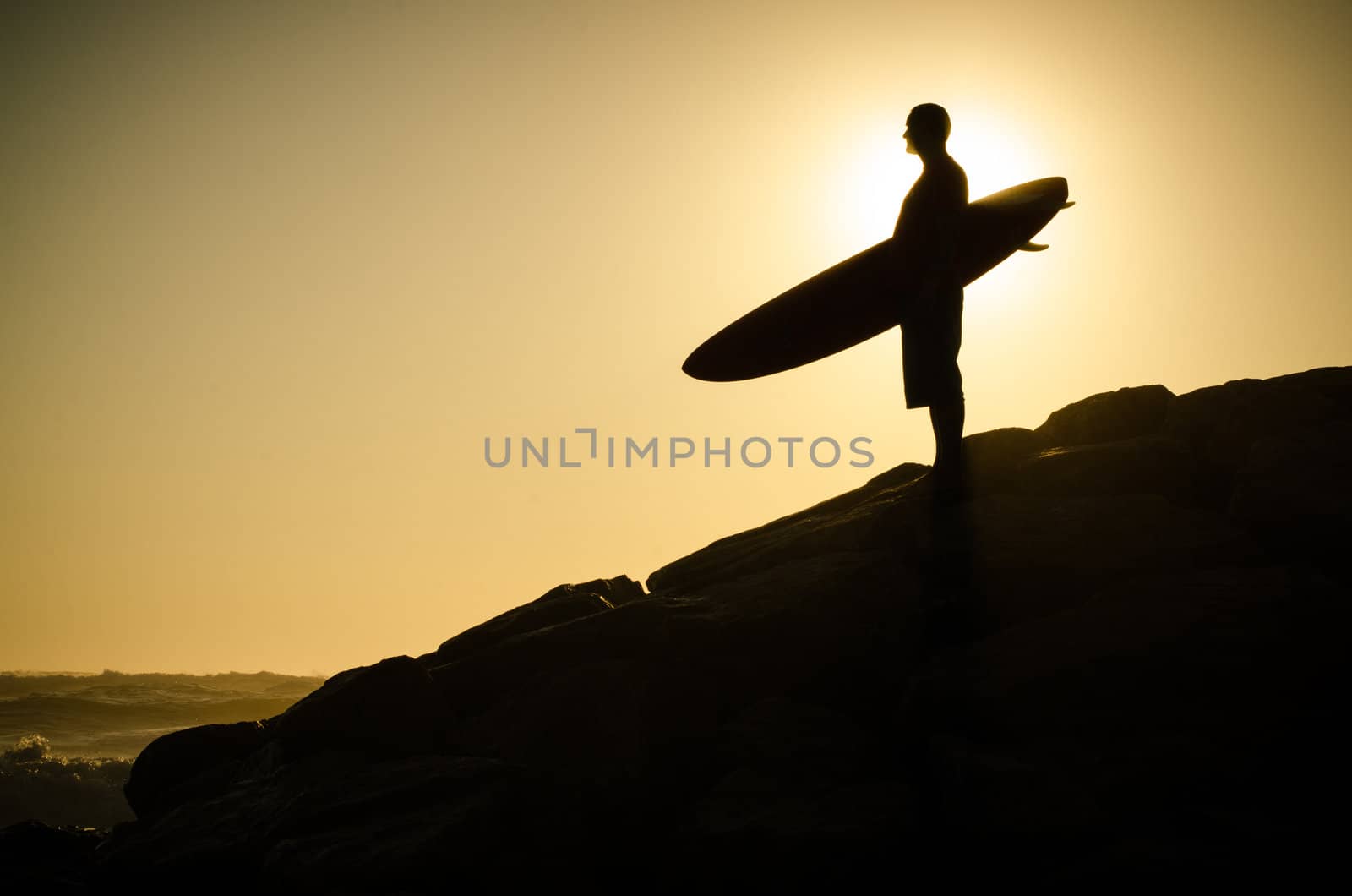 A surfer watching the waves at sunset in Portugal.