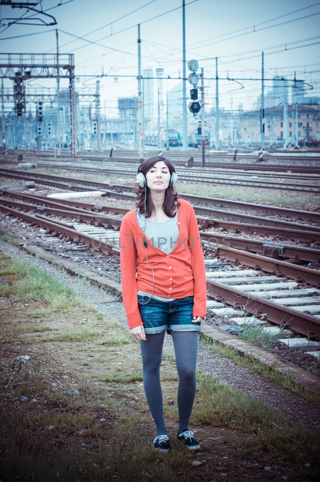 Beautiful stylish woman listening to music in railway