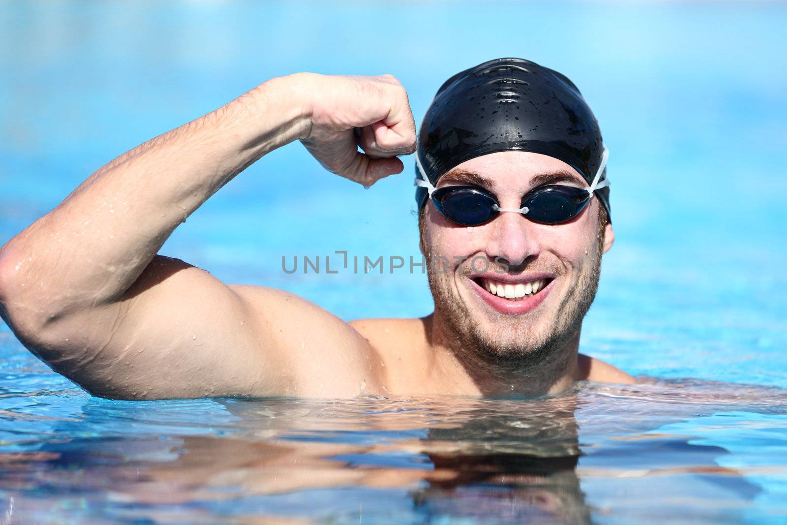 Sport swimmer winning. Man swimming cheering celebrating victory success smiling happy in pool wearing swim goggles and black swimming cap. Caucasian male fit fitness model.