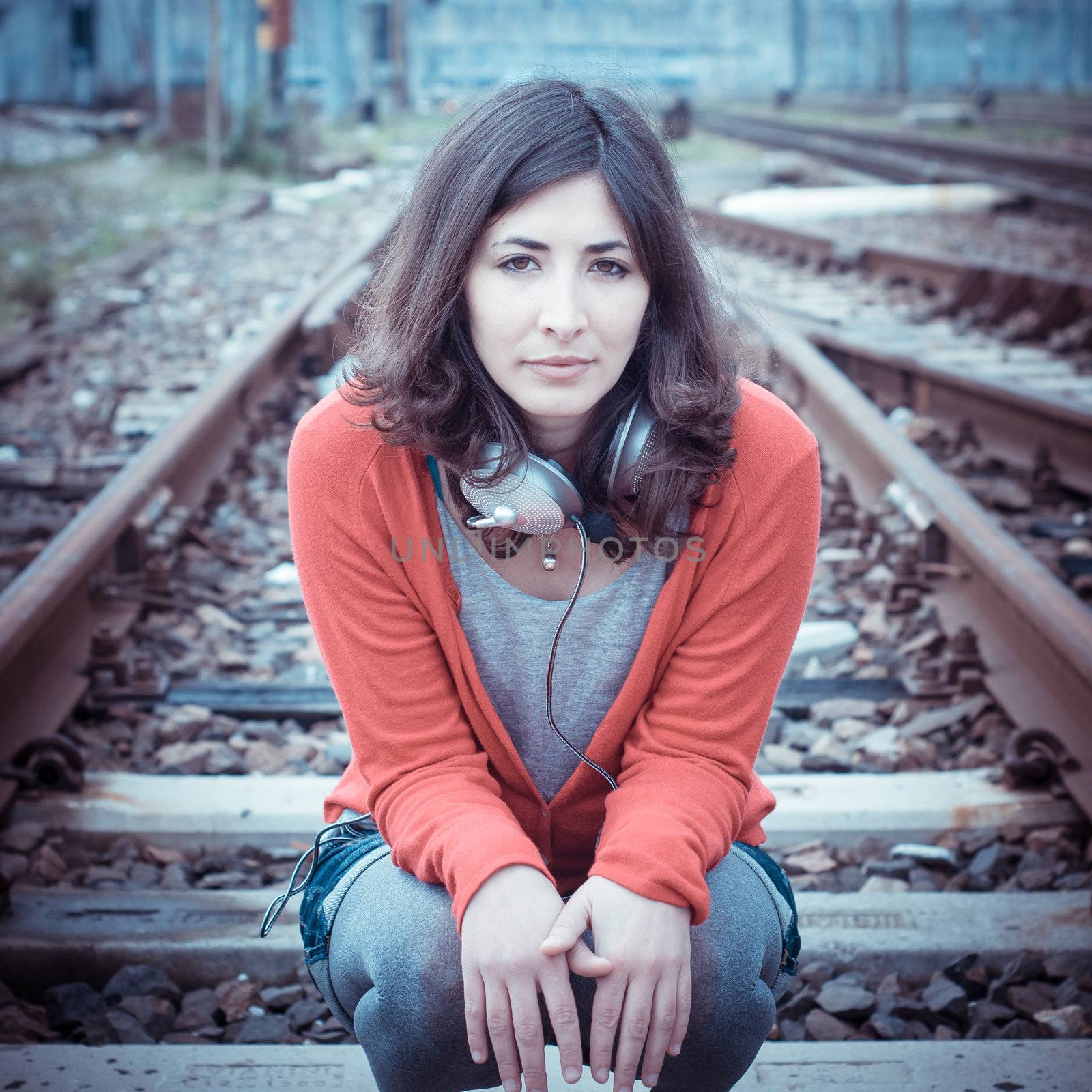 Beautiful stylish woman listening to music in railway
