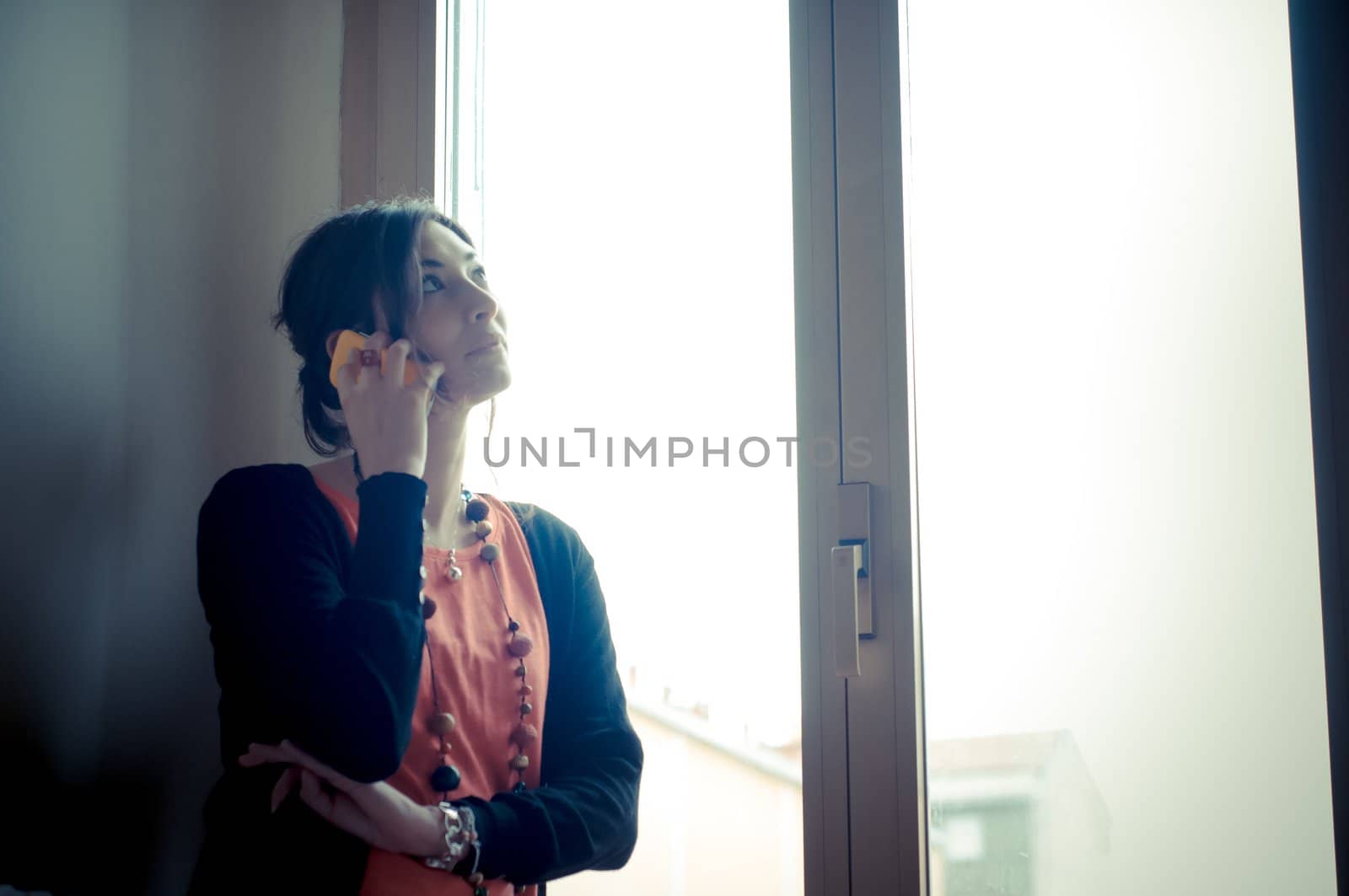 beautiful woman at home at the phone near window