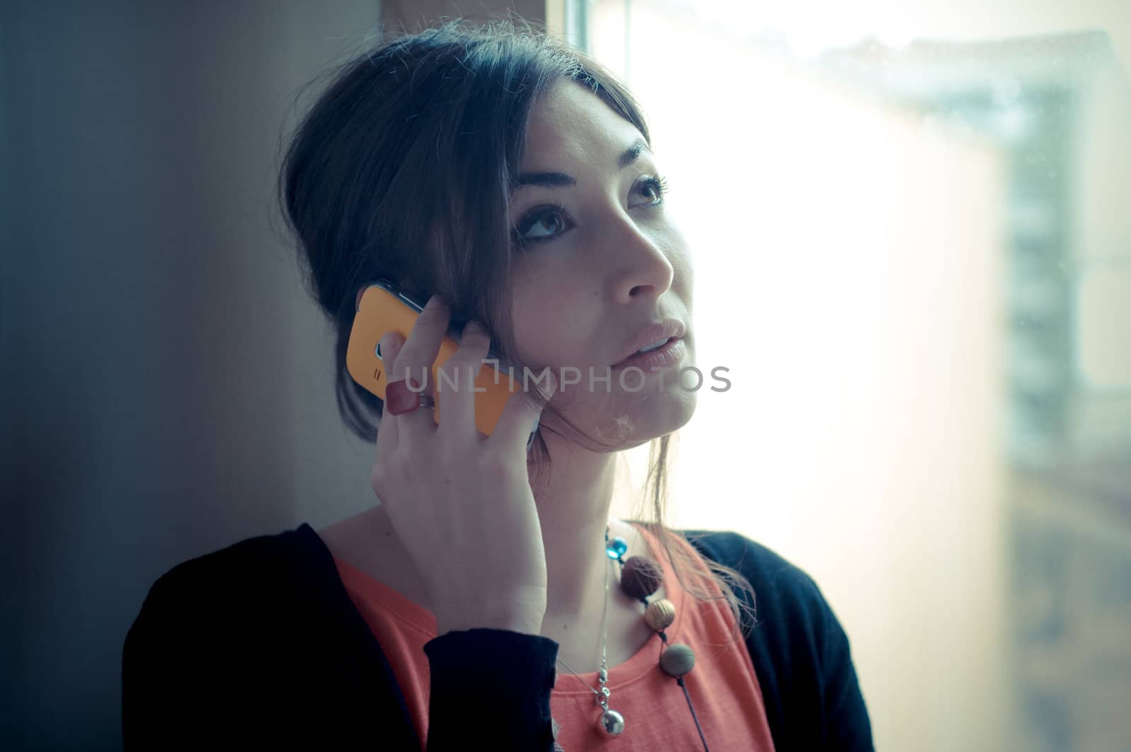 beautiful woman at home at the phone near window