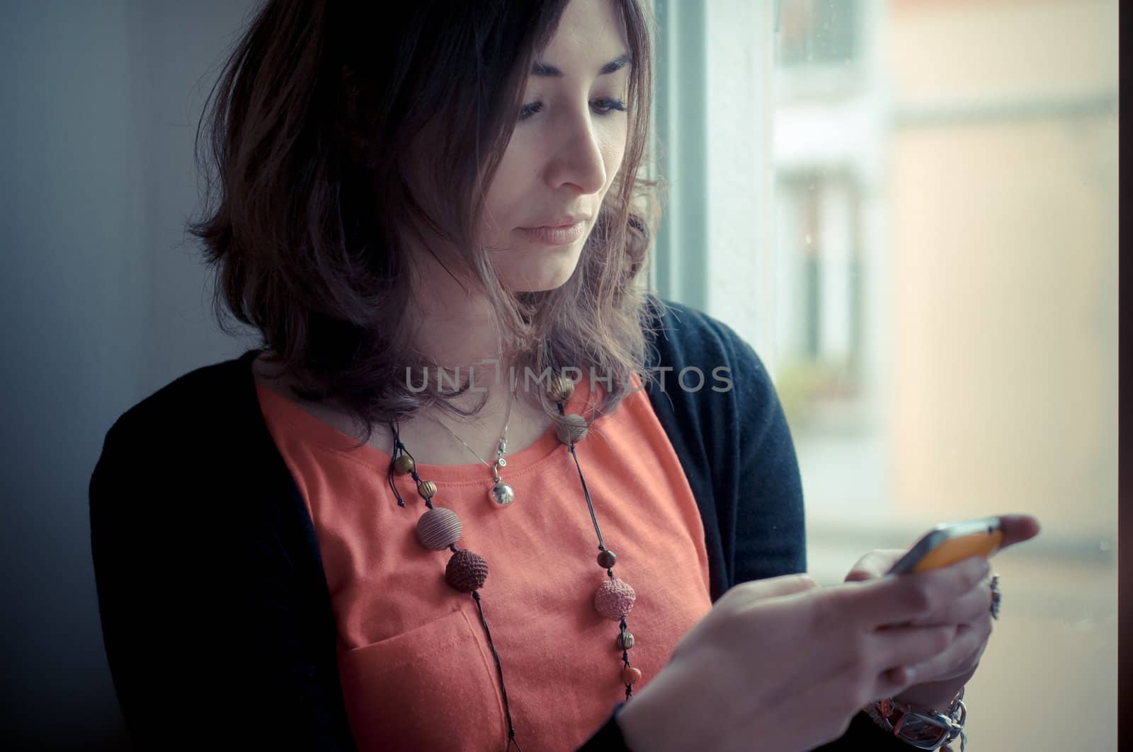 beautiful woman at home at the phone near window
