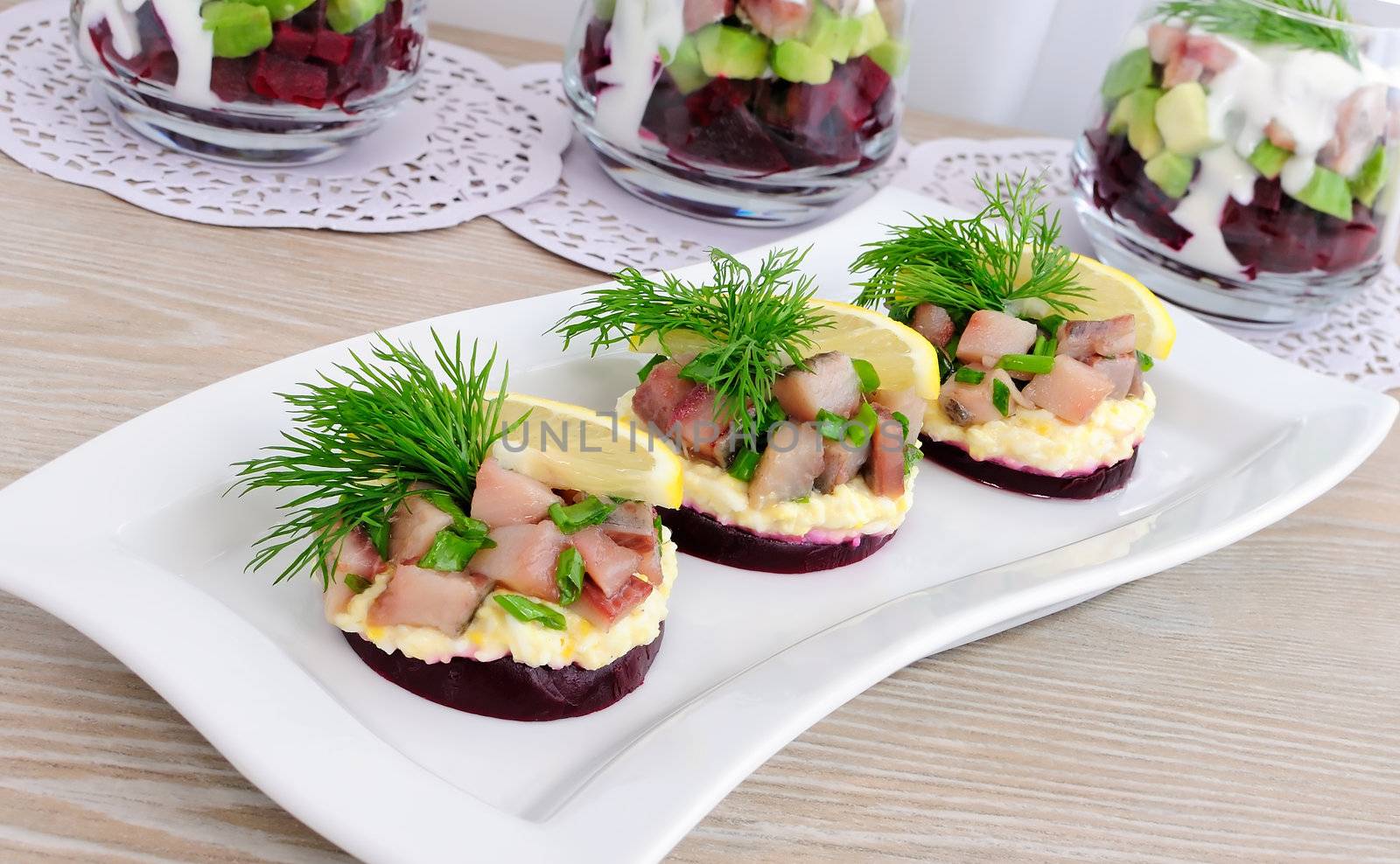 Appetizer of herring with onions on the beets and eggs, lemon and dill