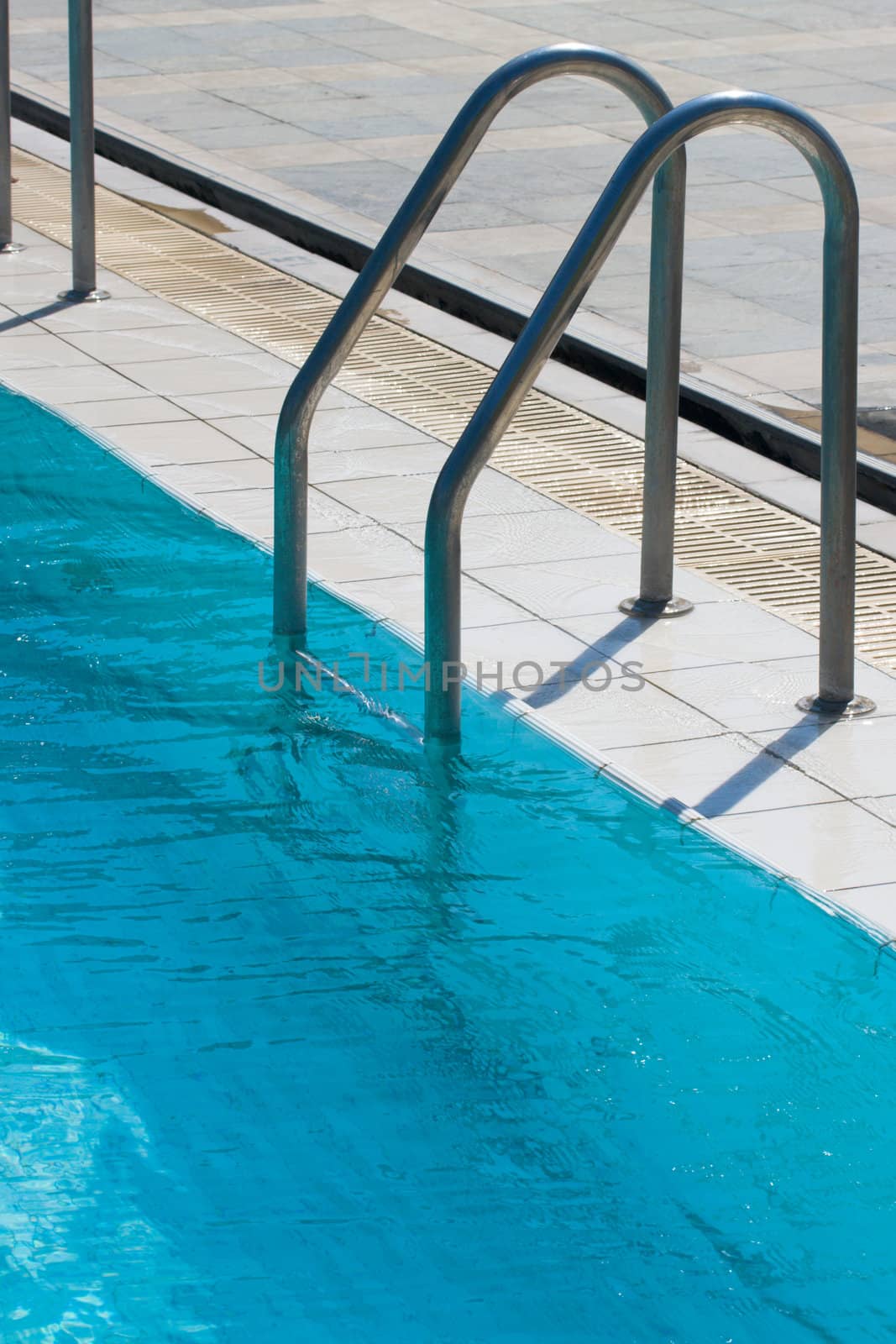 Metal ladder to swimming pool with blue water