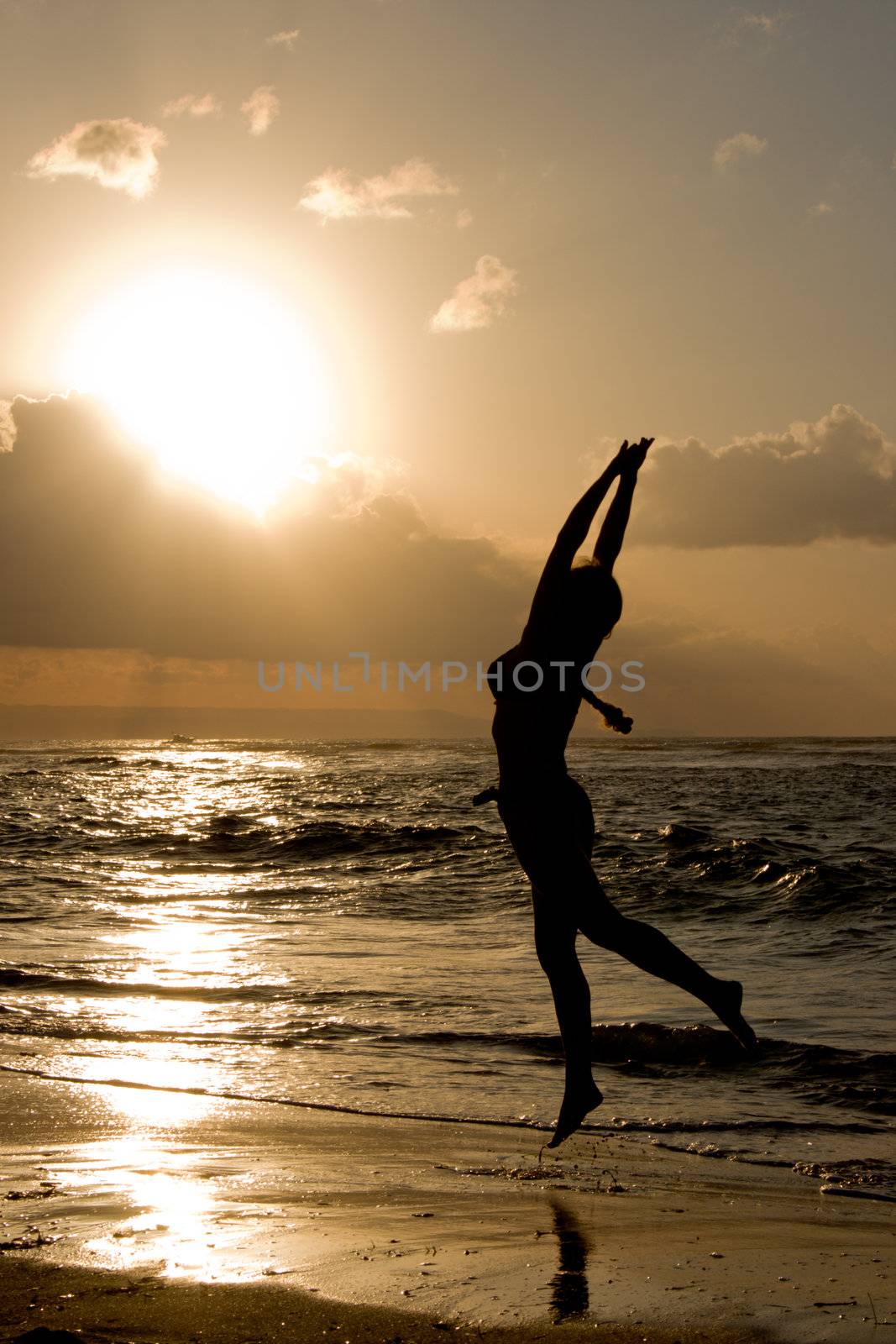 Girl jumping on sunrise at the beach