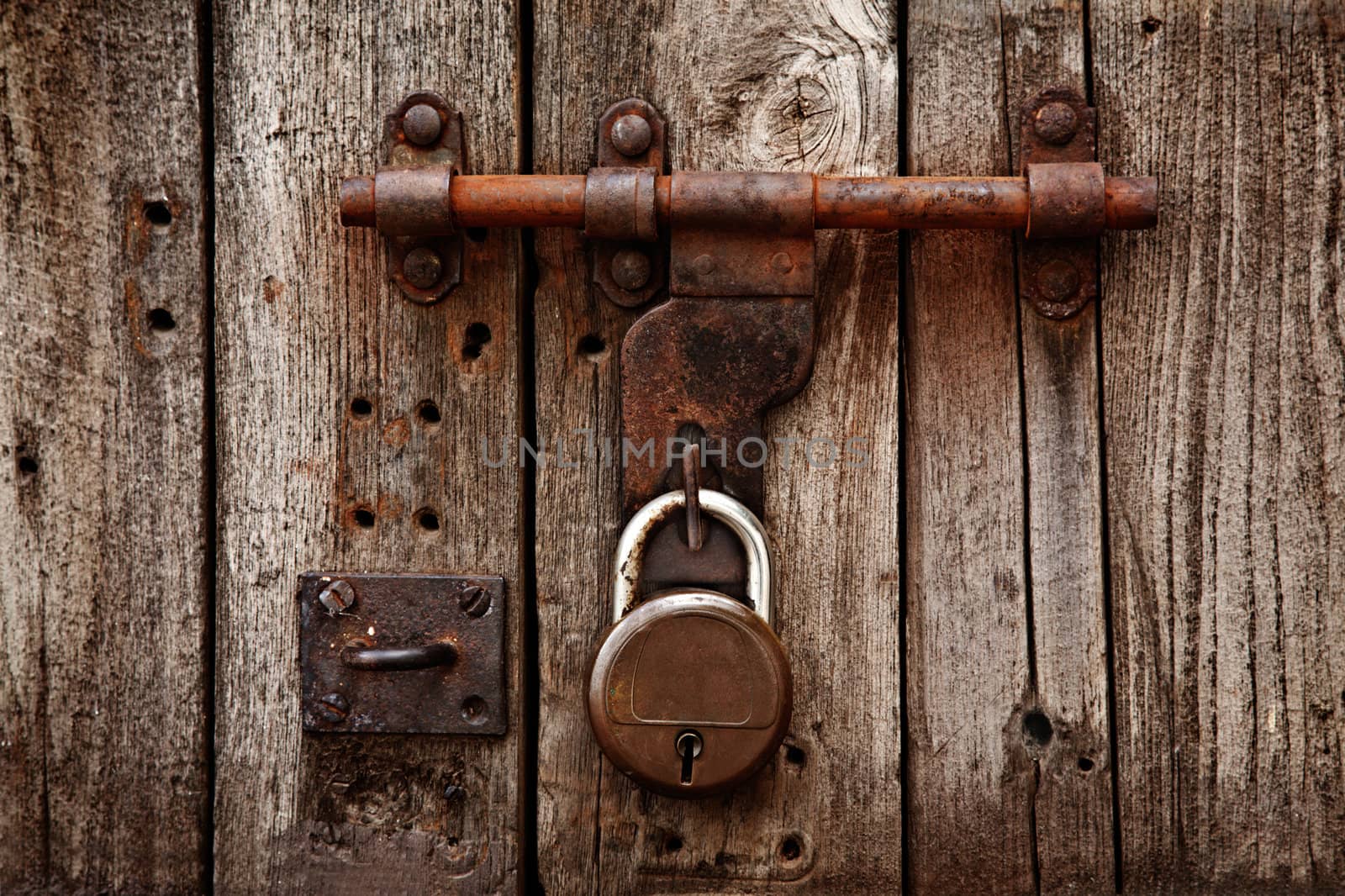 Old latch with padlock on gatees