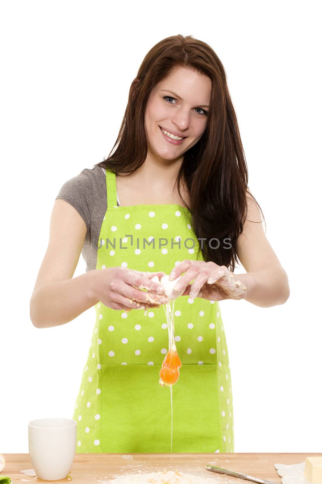 young beautiful woman adding egg to flour on white background