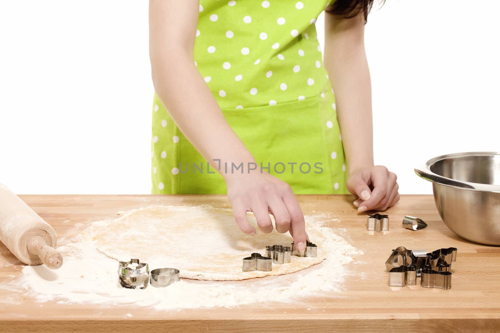 woman with green apron  pressing christmas molds in dough