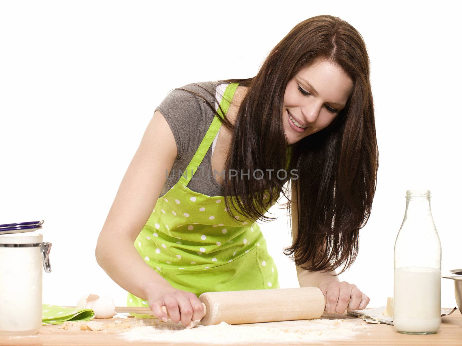 young happy woman using rolling pin on dough with white background