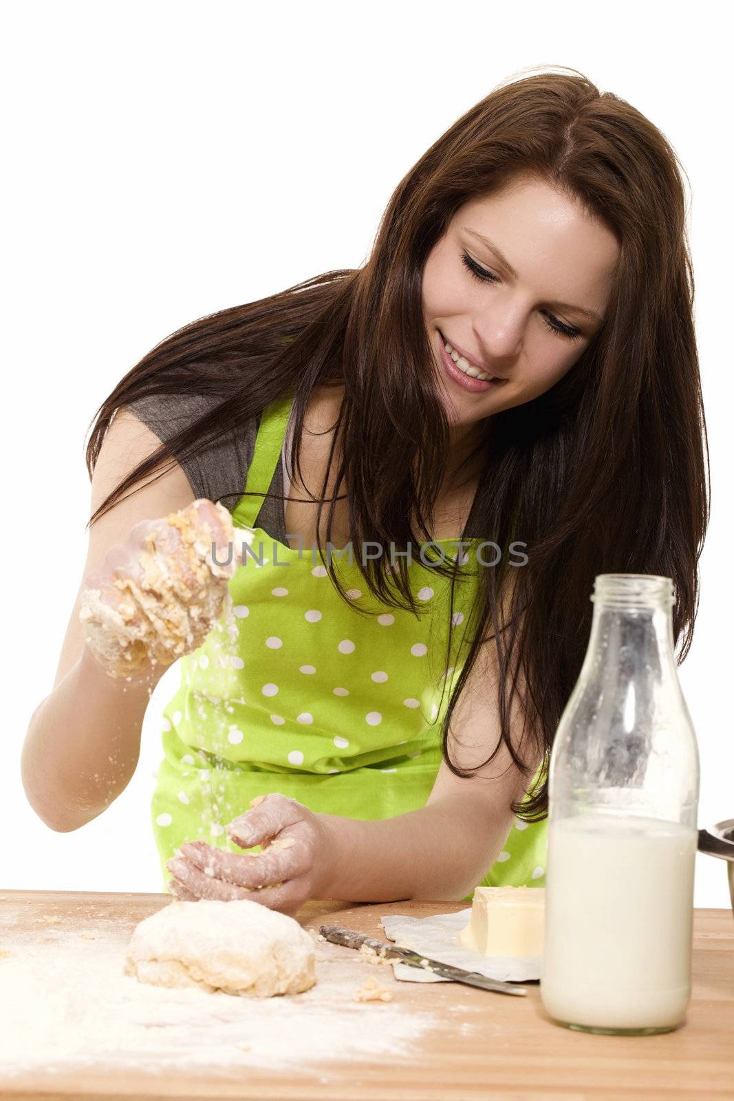 young woman adding flour to dough by RobStark