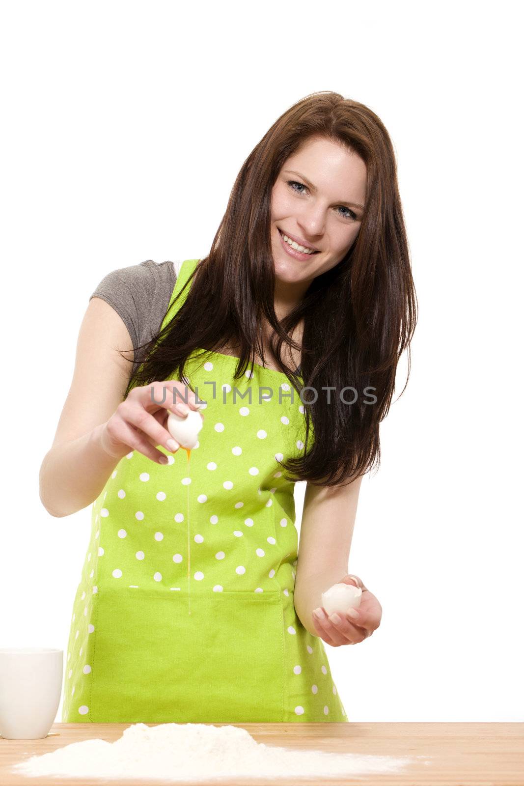 young woman adding an egg to flour by RobStark