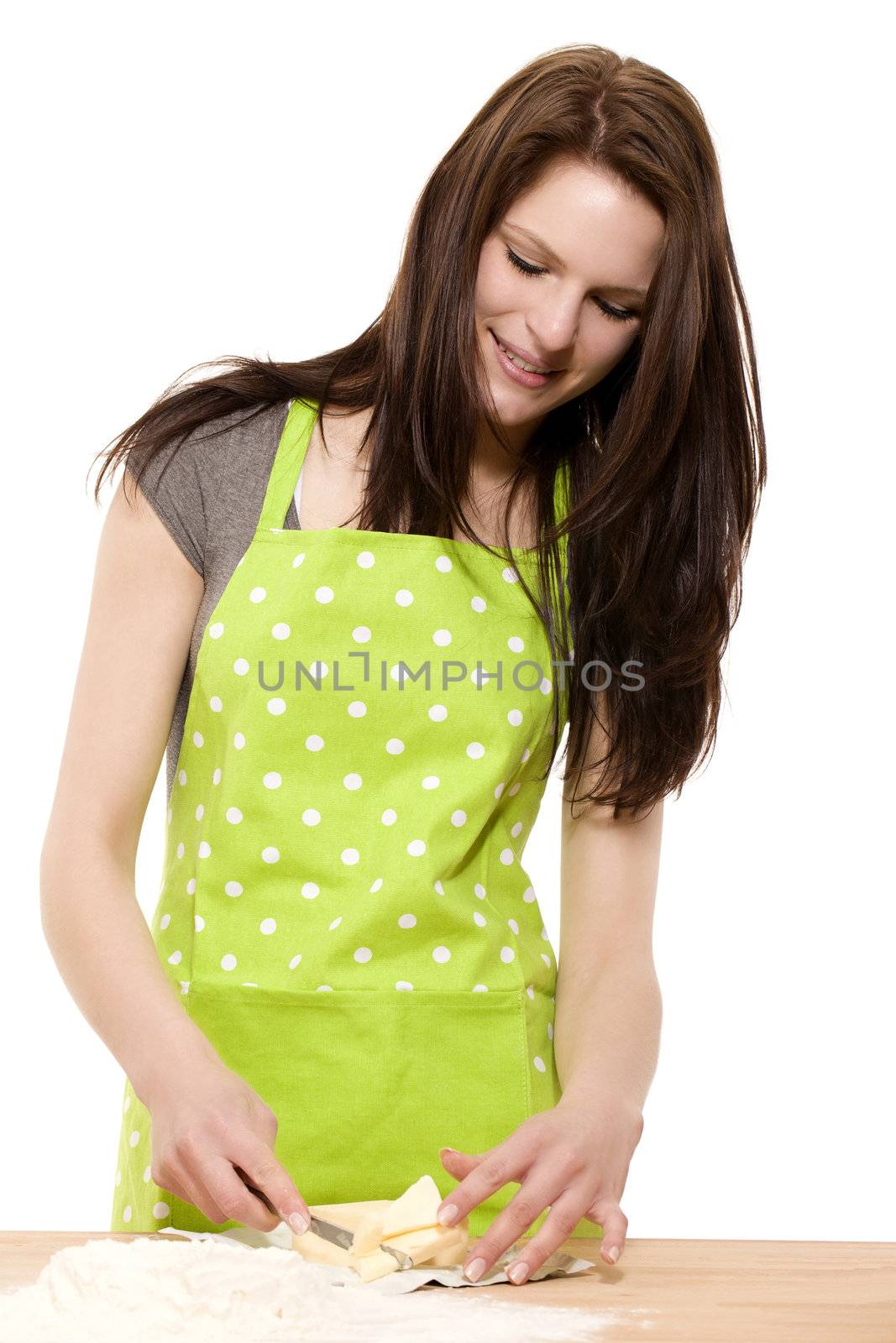 young smiling woman cutting butter or shortening for baking on white background