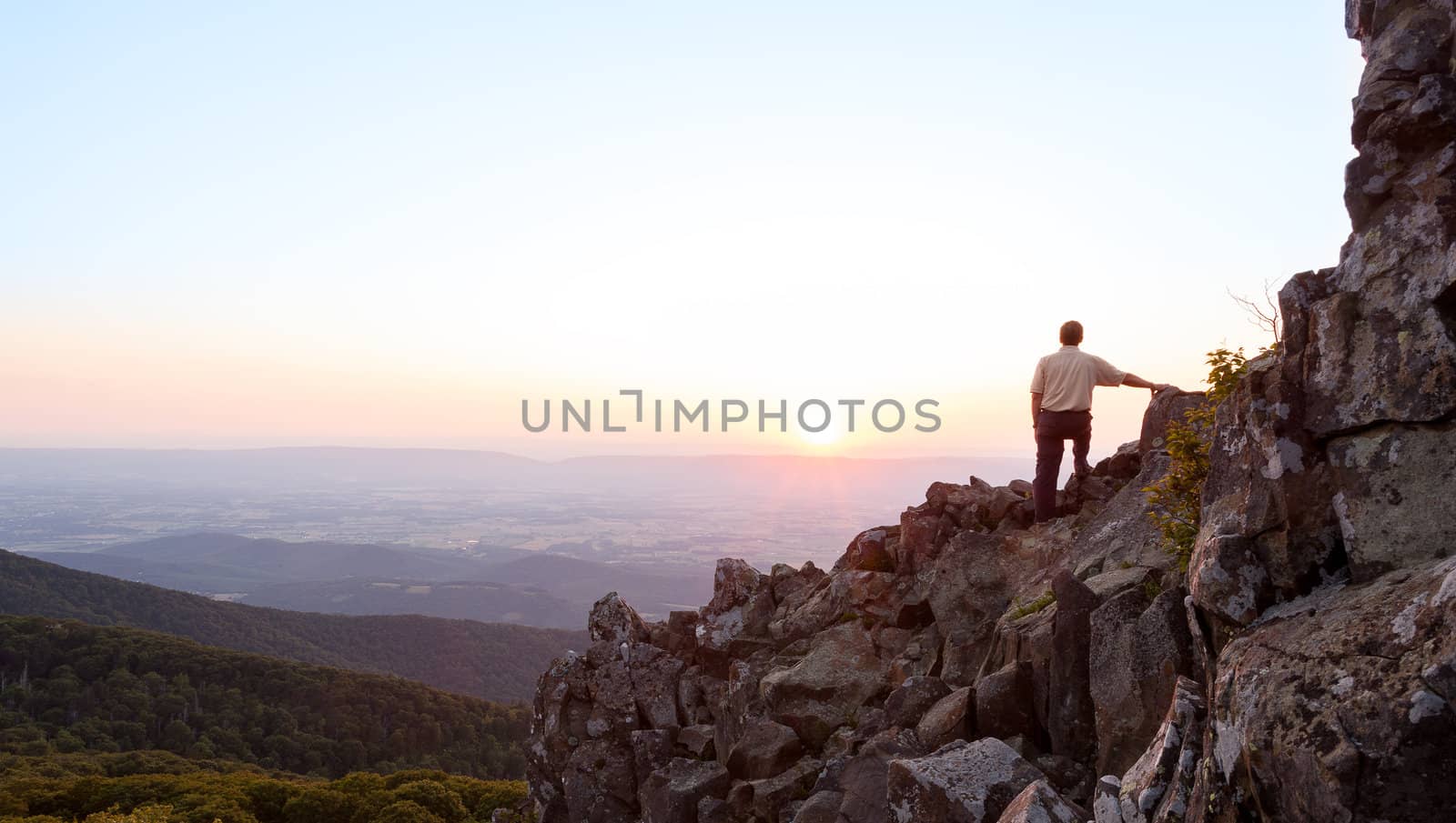 Back view of man watching sunset from rocky summit of Stony Man on Skyline Drive in Virginia