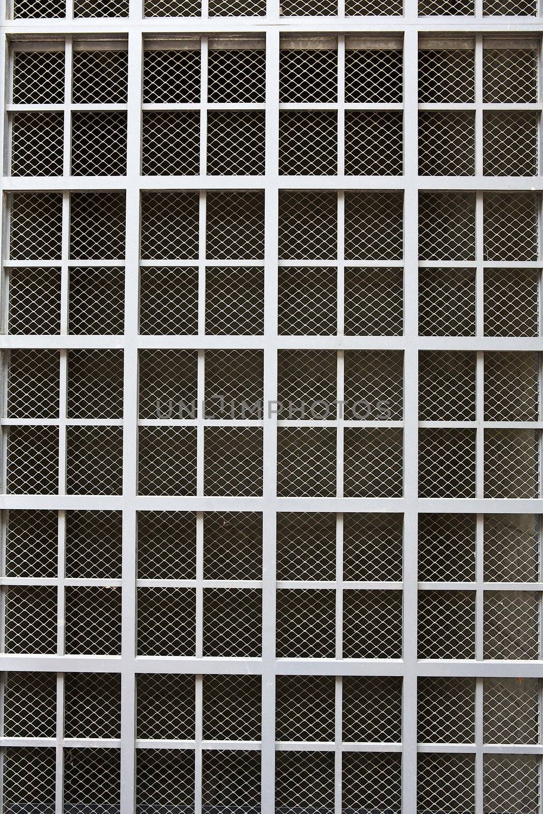 Dull silver color metal bars over screen covering building window