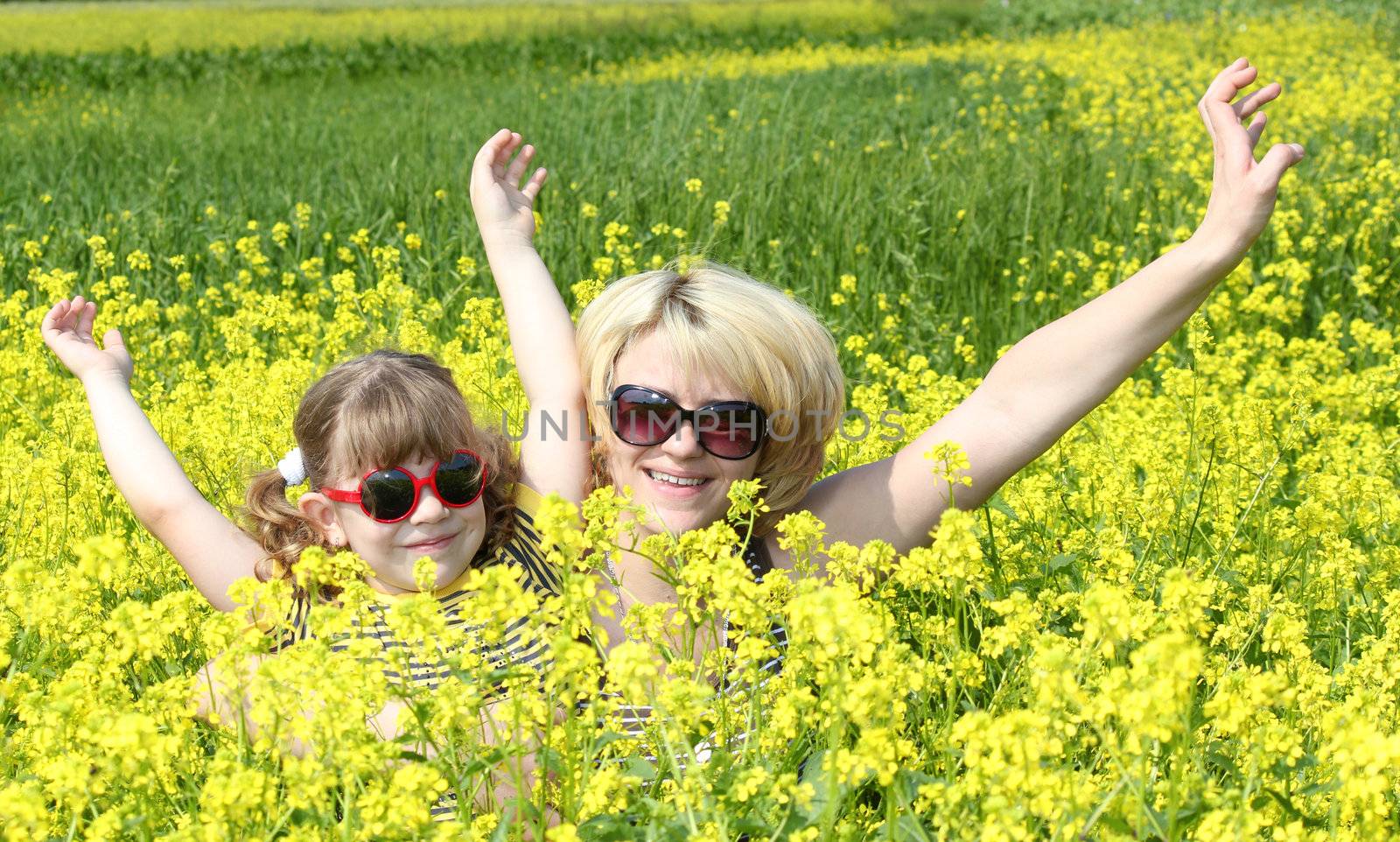 mother and daughter in yellow flower field by goce