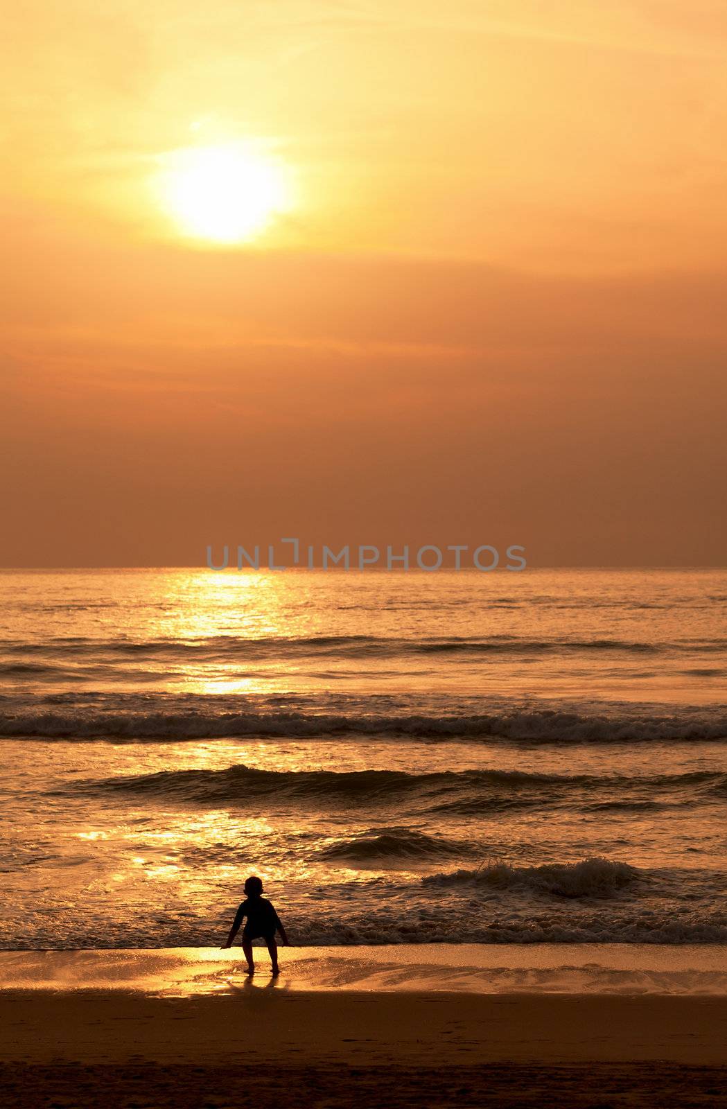 A child plays with the waves on the evening beach