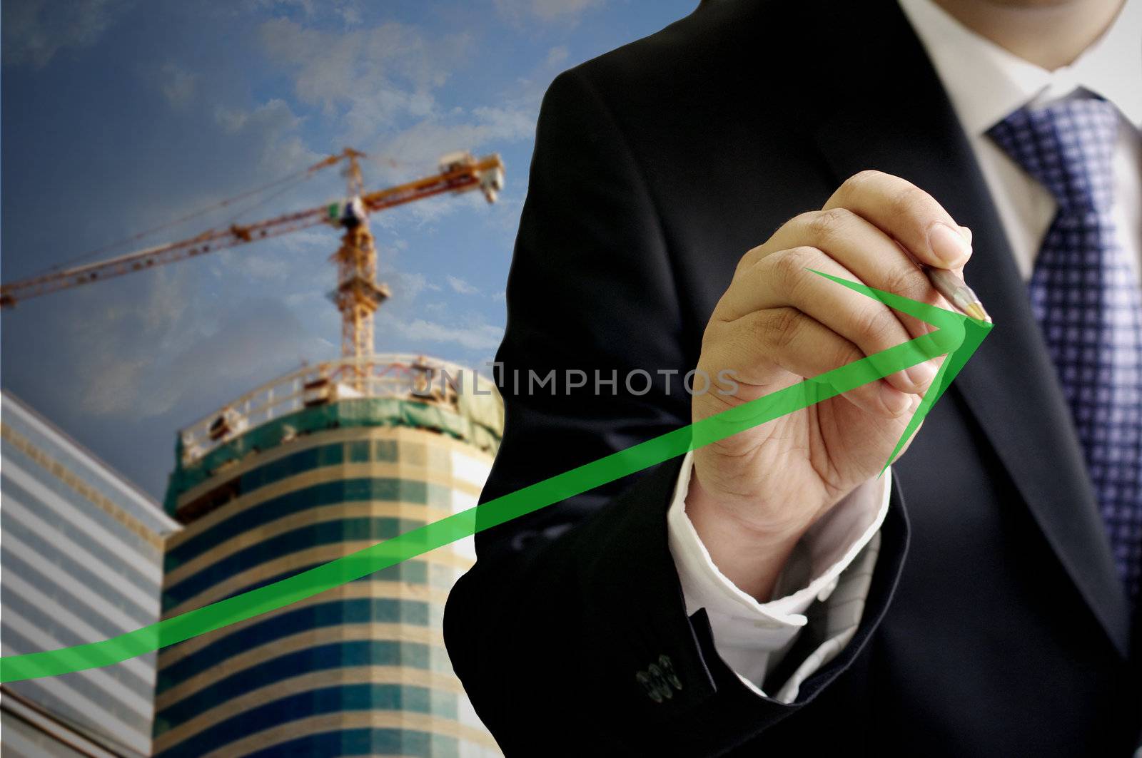 Businessman write a grow up green arrow with construction site background by pixbox77
