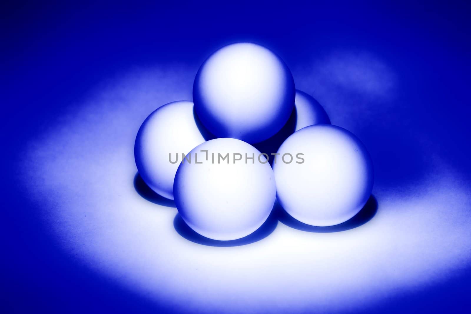 four white balls for table tennis built a pyramid and illuminated from beneath blue light