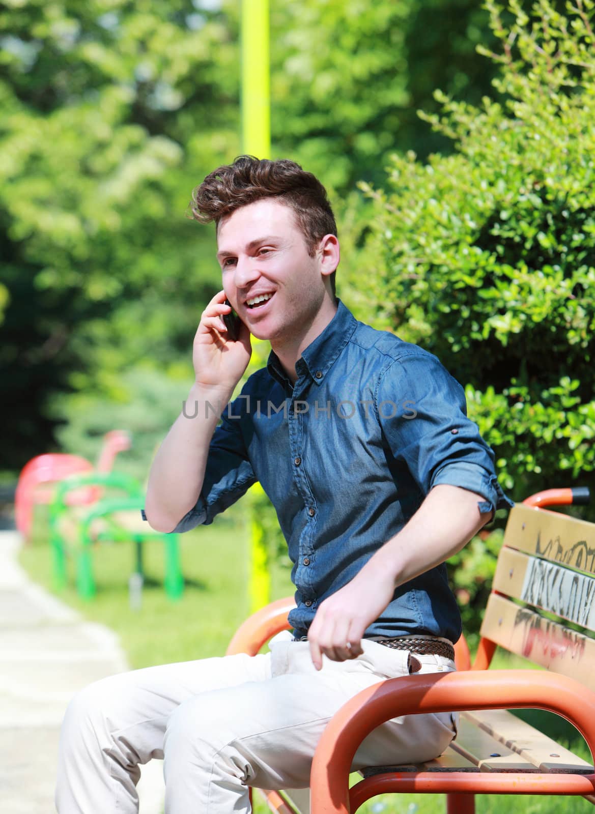 Happy young man in the park with telephone