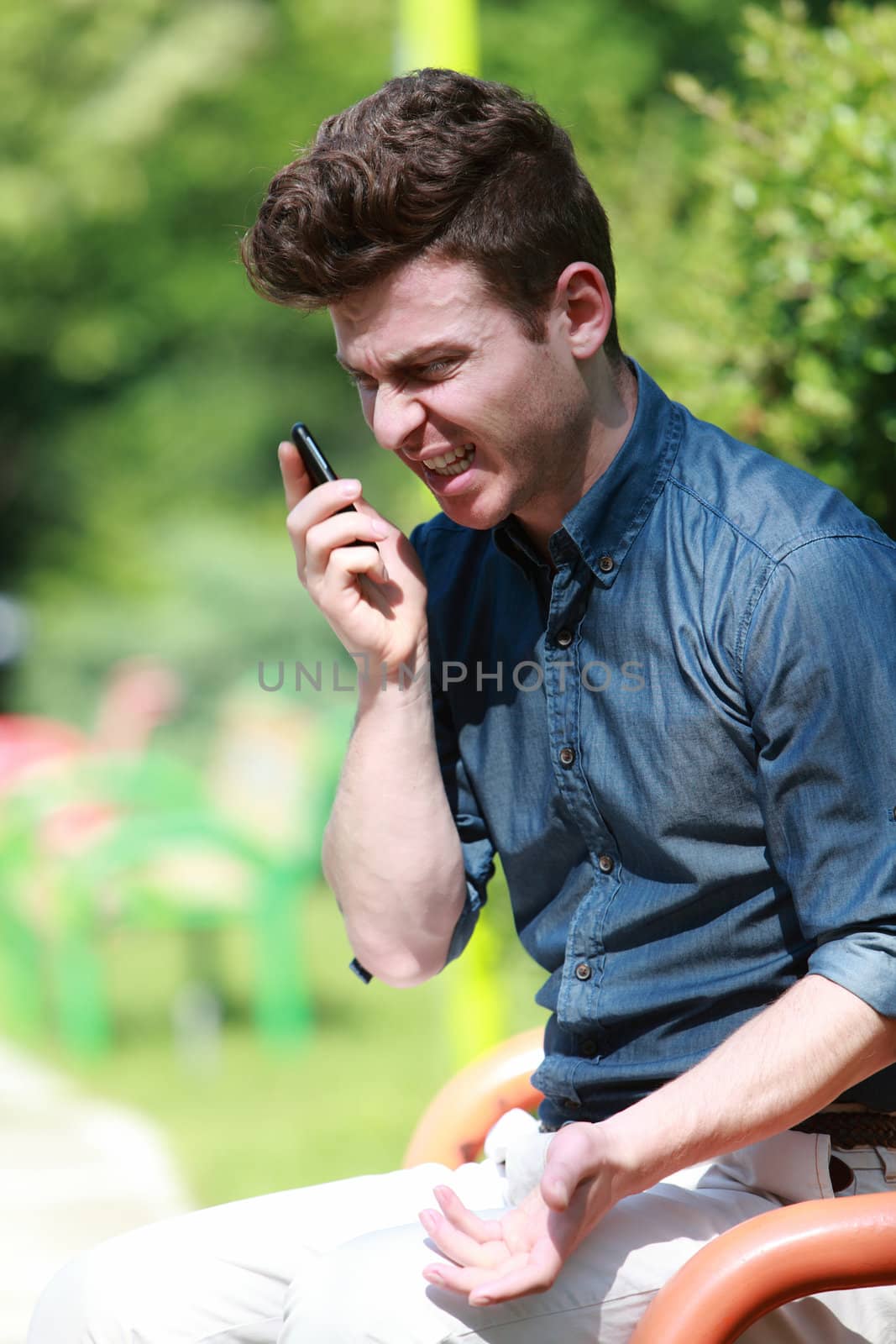 Young man in park angry on telephone