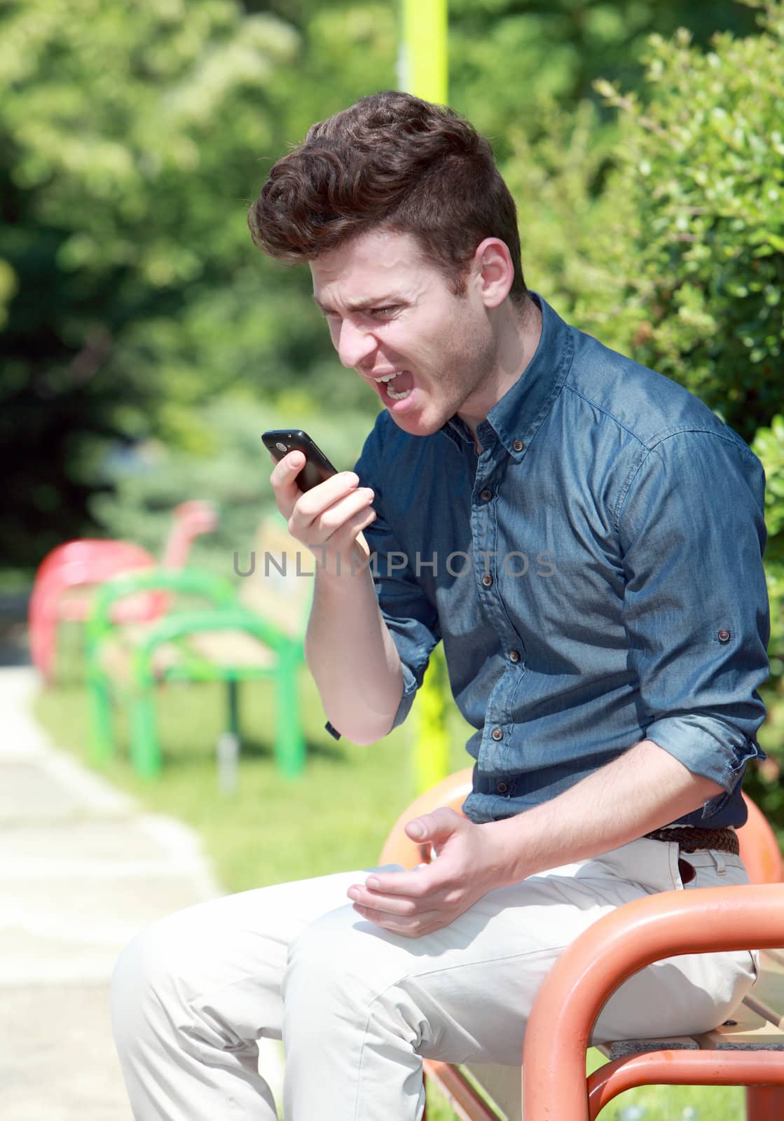 Youn russian man shouting on telephone in park