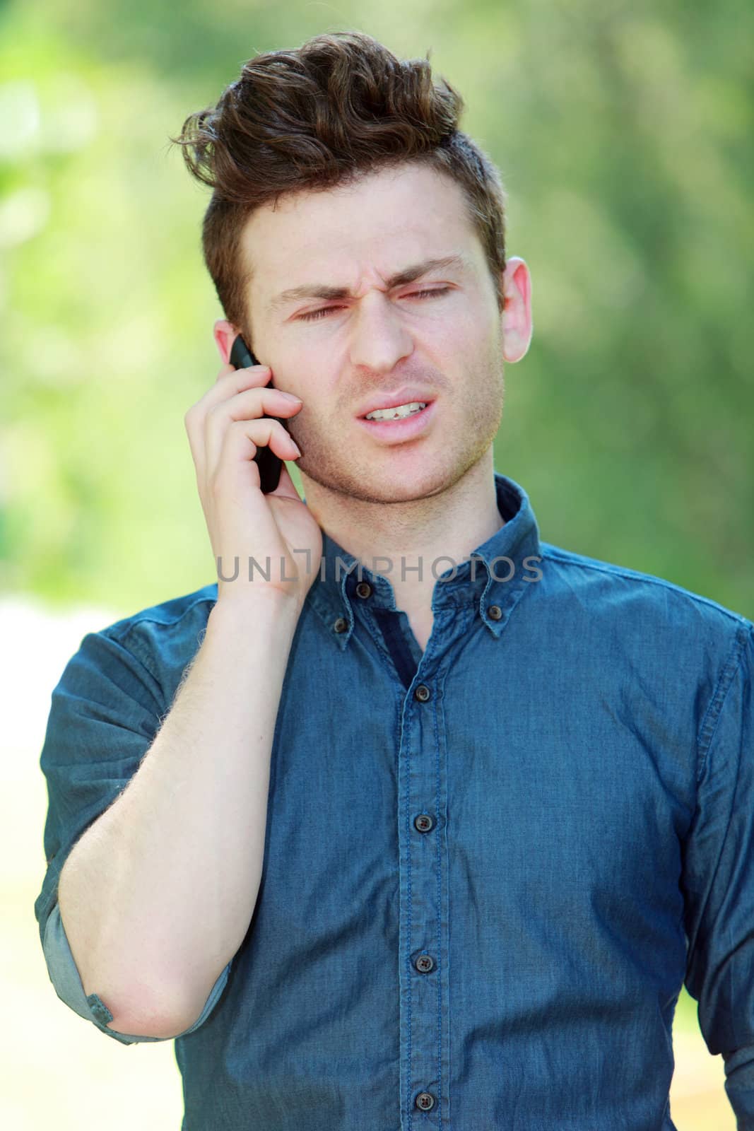Disappointed young man at telephone by shamtor