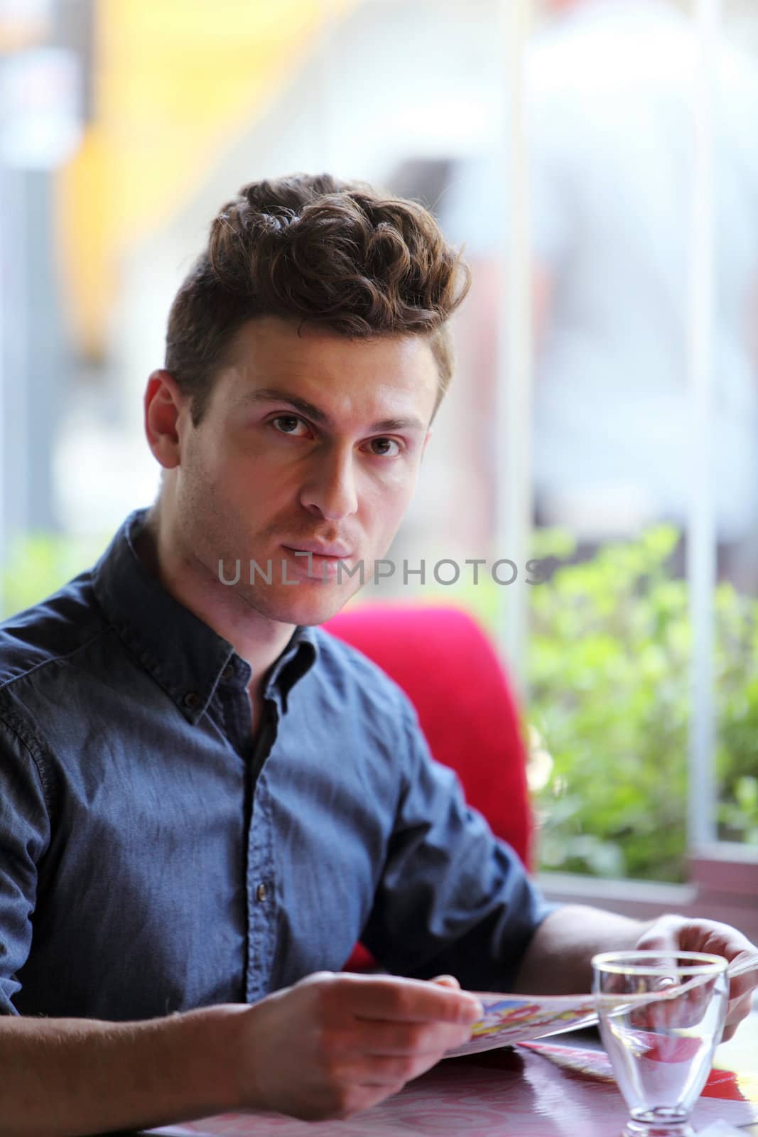 Young handsome man in restaurant ordering from menu