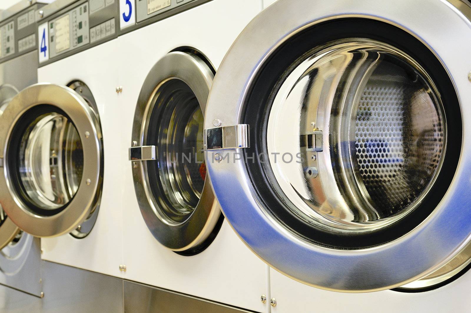 A row of industrial washing machines in a public laundromat 