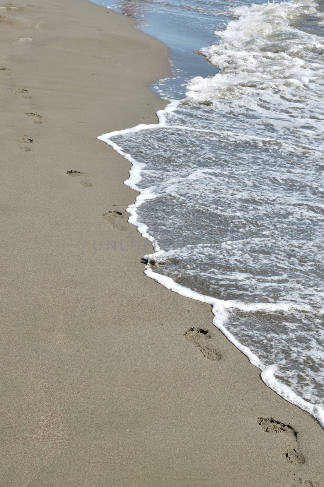 Footprint on the sandy beach and sea wave