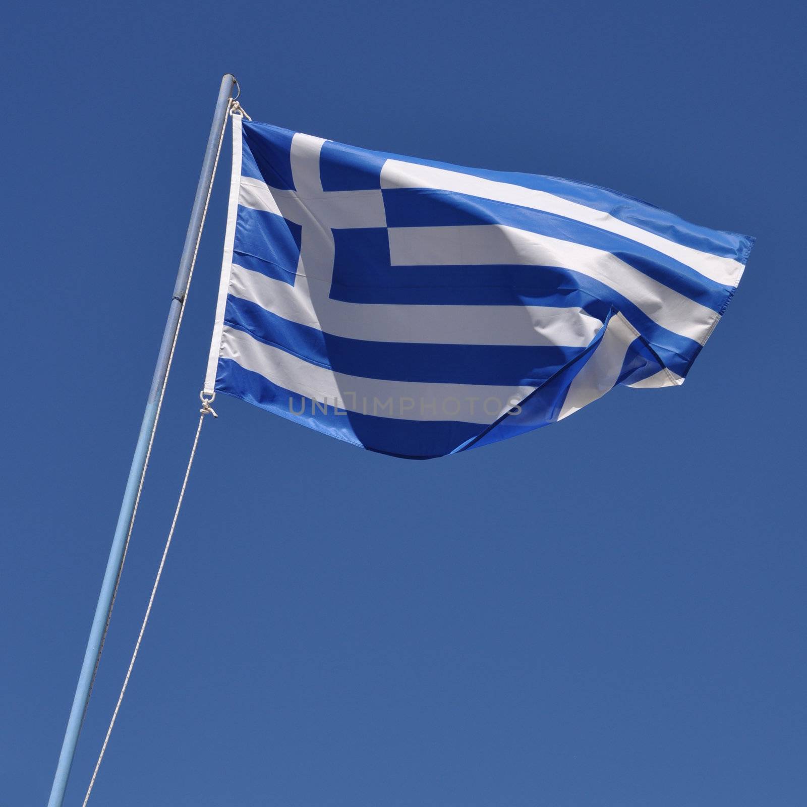vibrant greek flag on a blue pole against a blue sky background