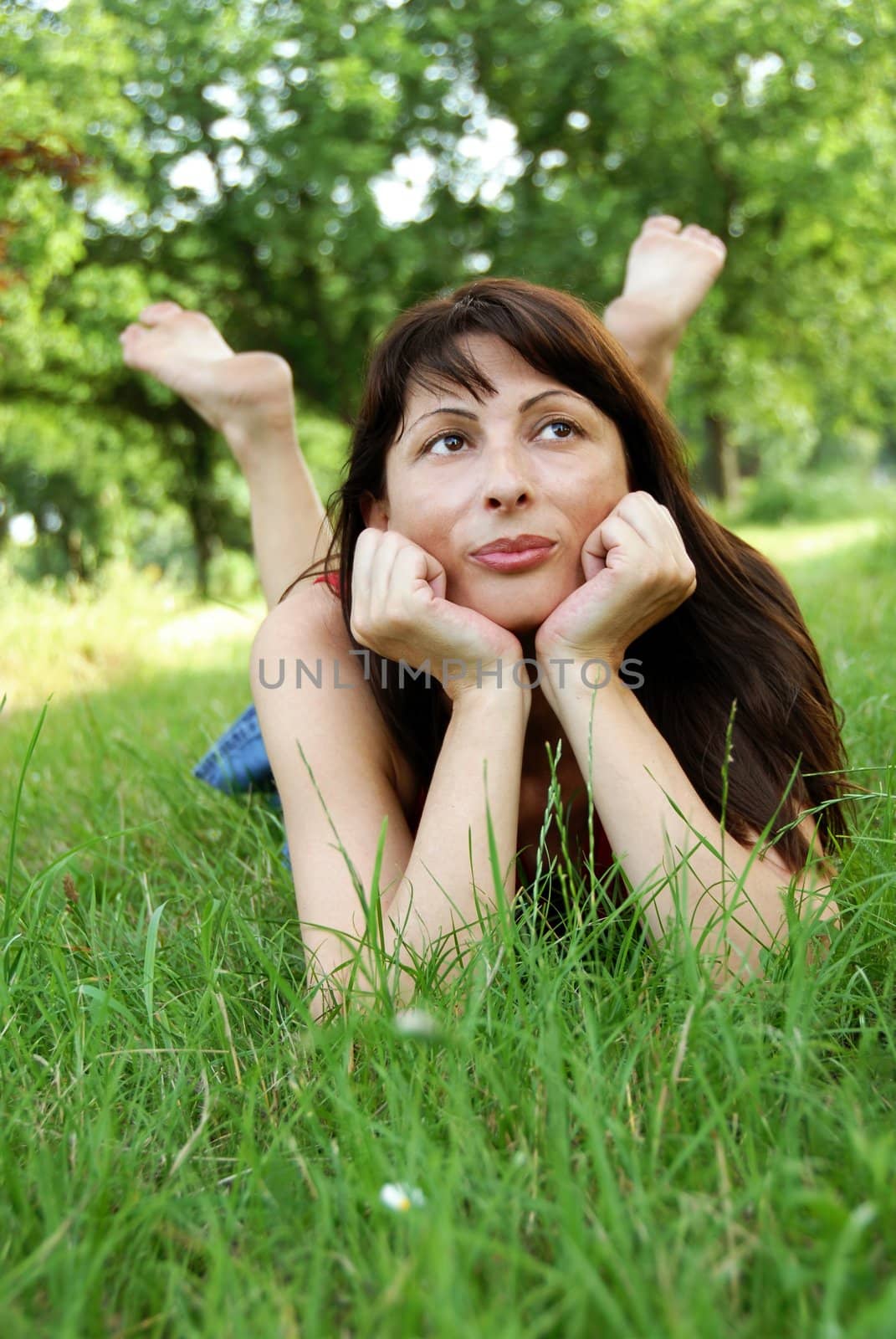 barefooted caucasian brunette woman lying in grass enjoying and dreaming