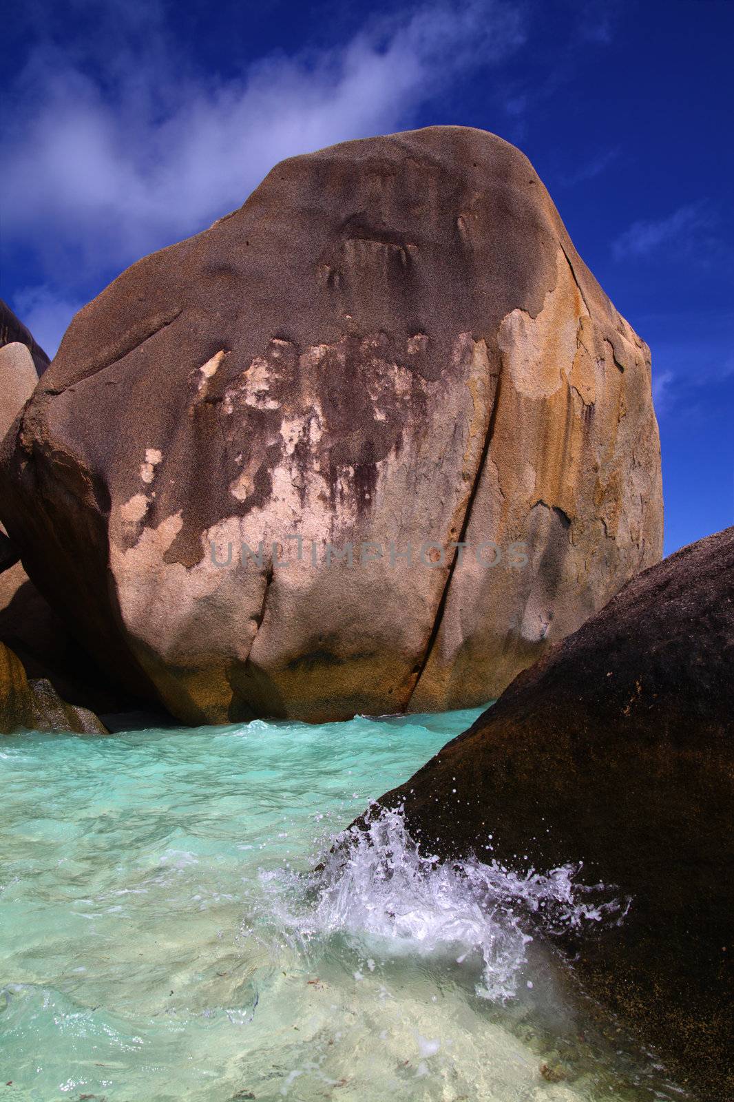 Clear tropical ocean water around large rocks on an island shore