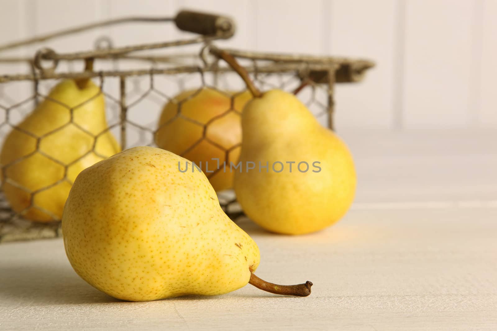 Fresh ripe pears in metal basket on table