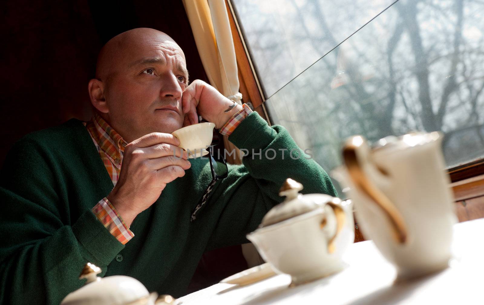 Close-up of adult man travelling and drinking coffee in old train