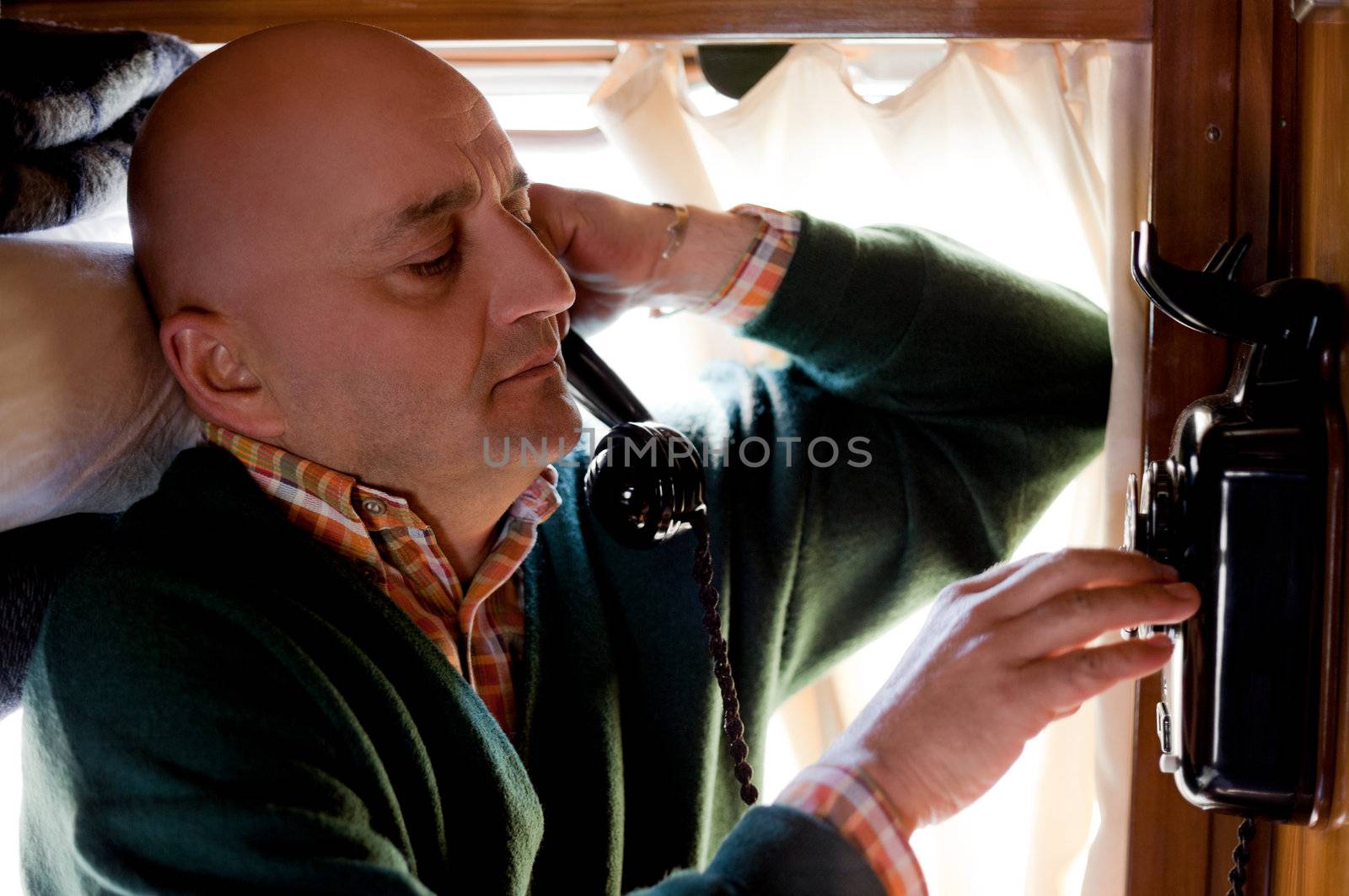 Adult man dialling a number on stationary telephone in old train
