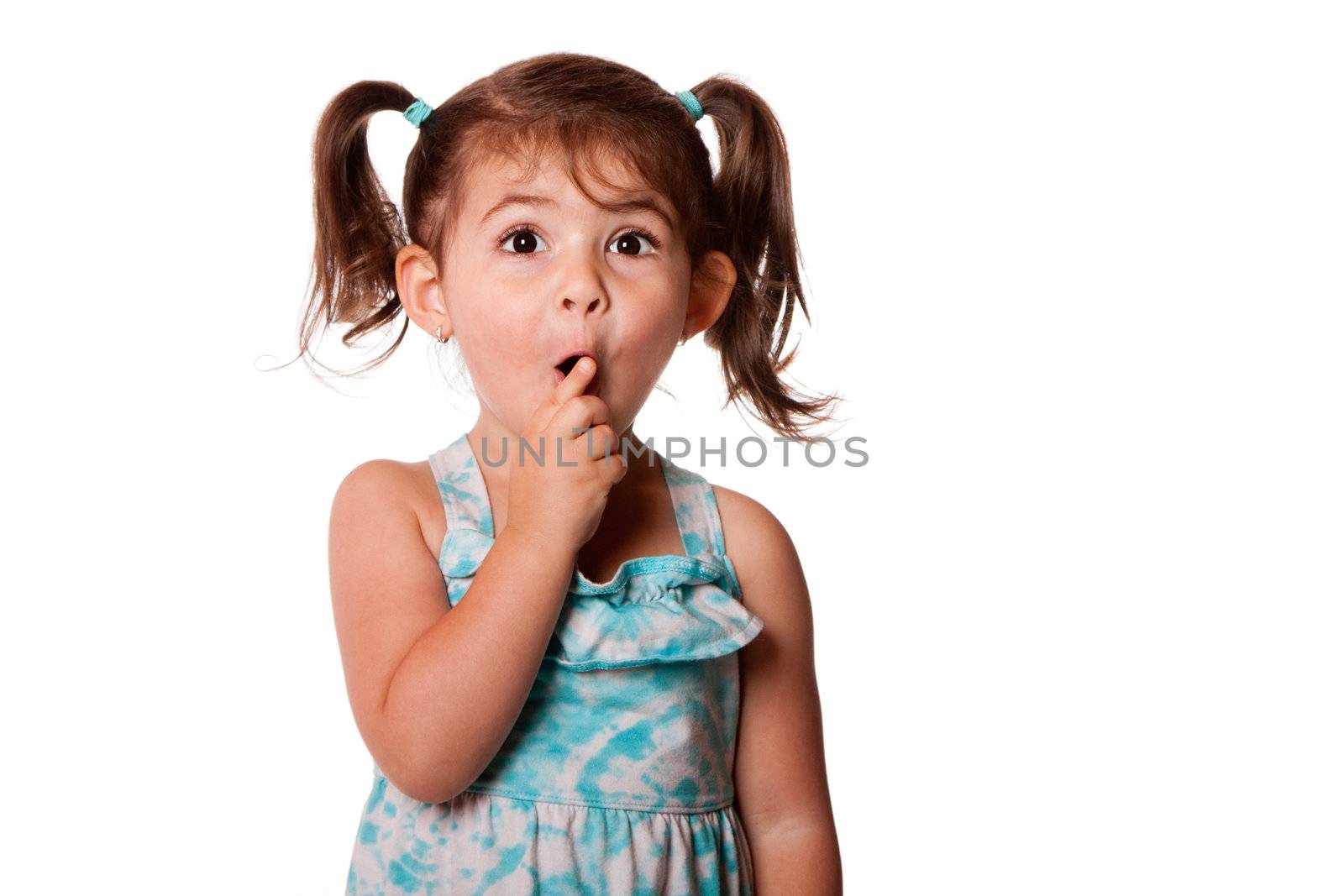Cute surprised little toddler girl with finger in front of mouth making silence shhh gesture, isolated.