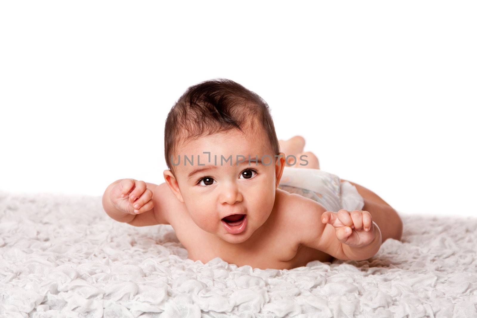 Cute happy baby laying on belly on soft surface wearing diaper, looking at camera, isolated.