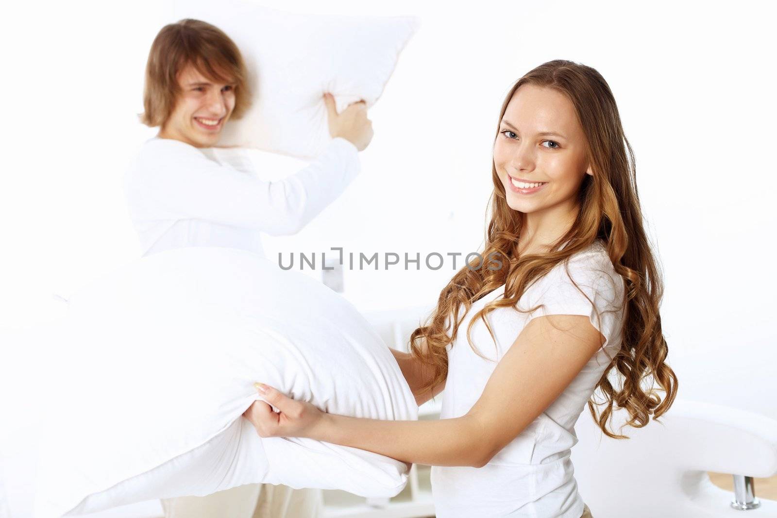 Young couple having fun with pillows at home